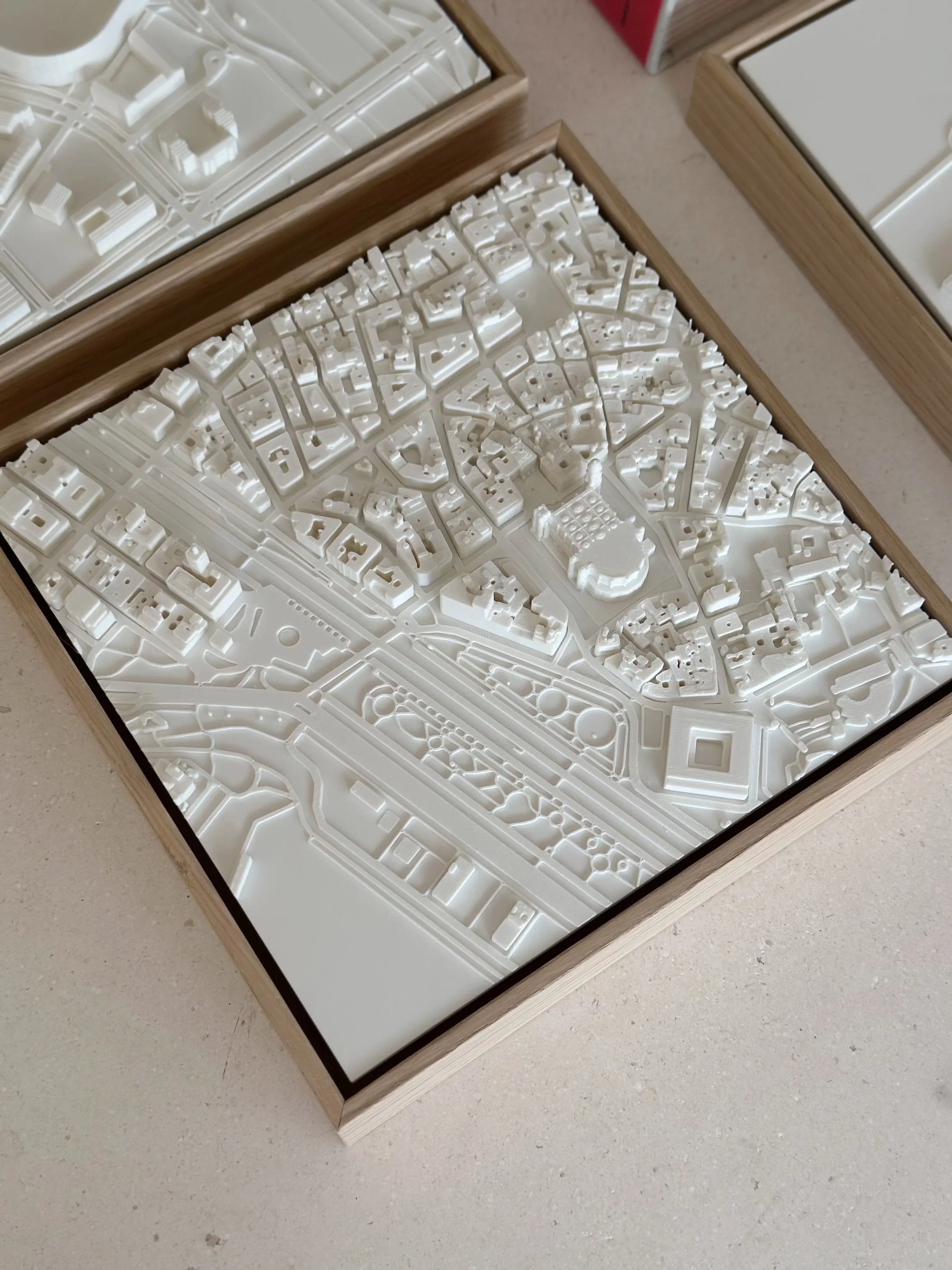 3D city map wall art in white, showing detailed urban streets and buildings in a wooden frame