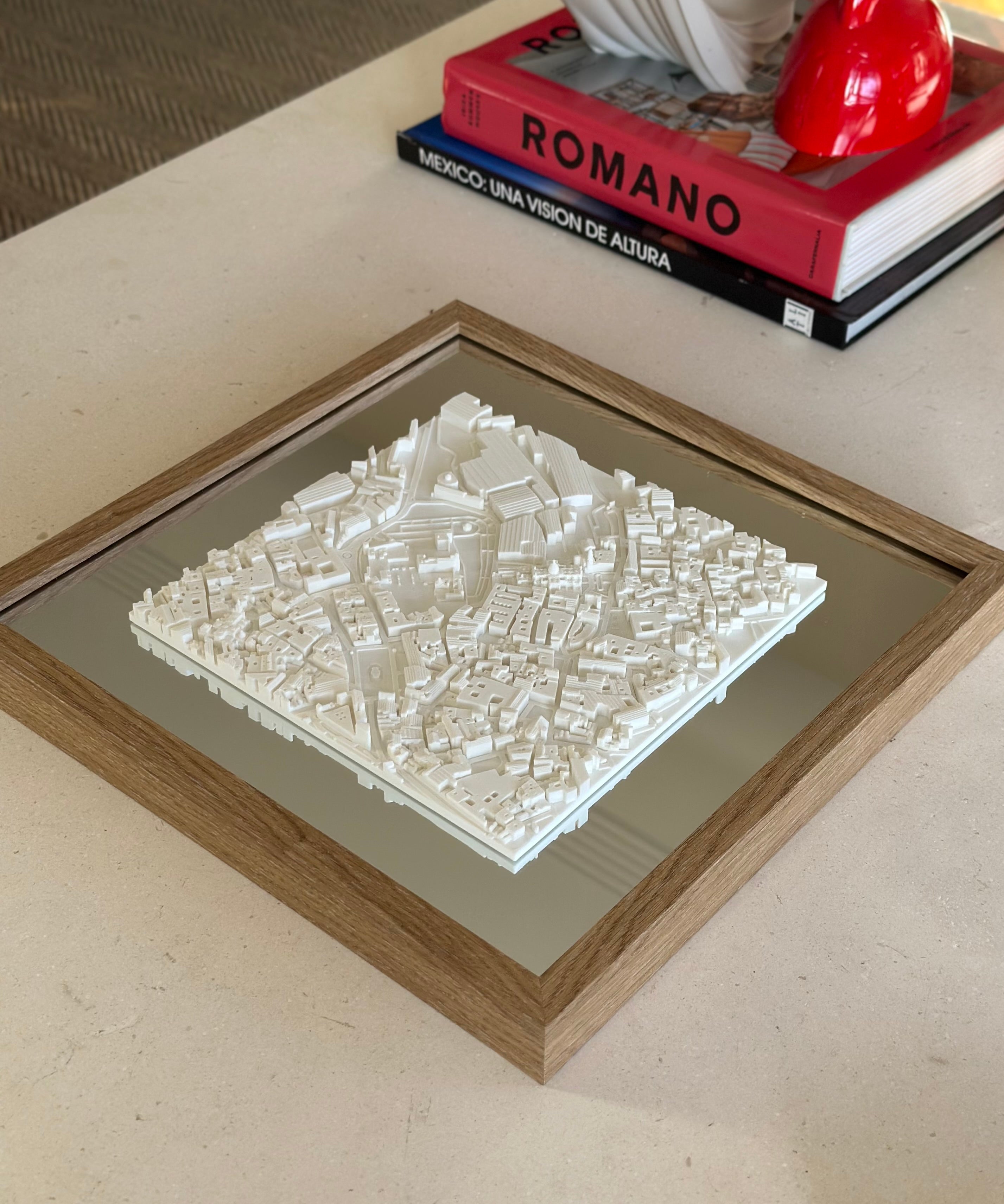 Framed 3D city map wall art with white buildings, displayed on a modern coffee table