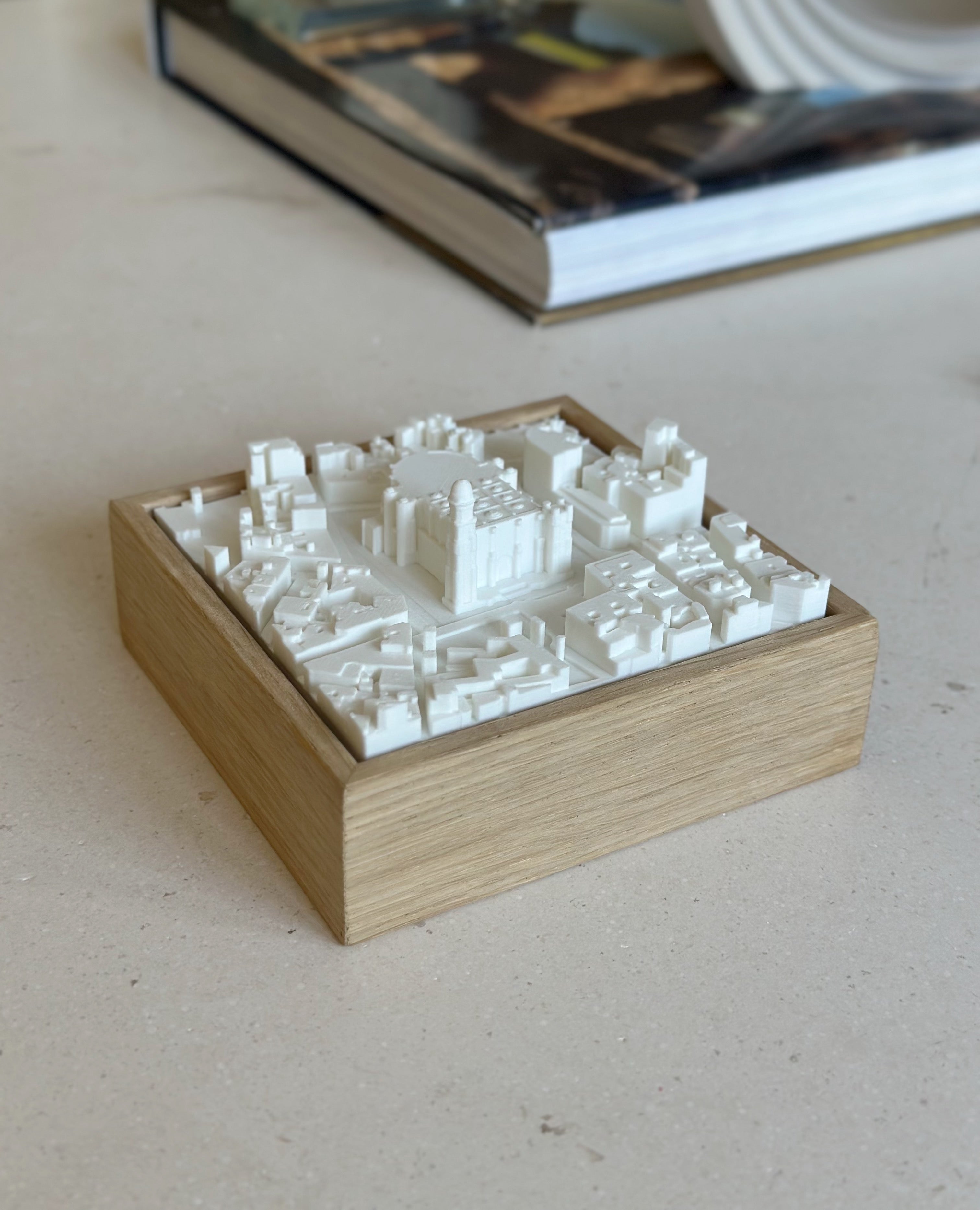 3D city map wall art in a wooden frame on a light table, decorative urban model.