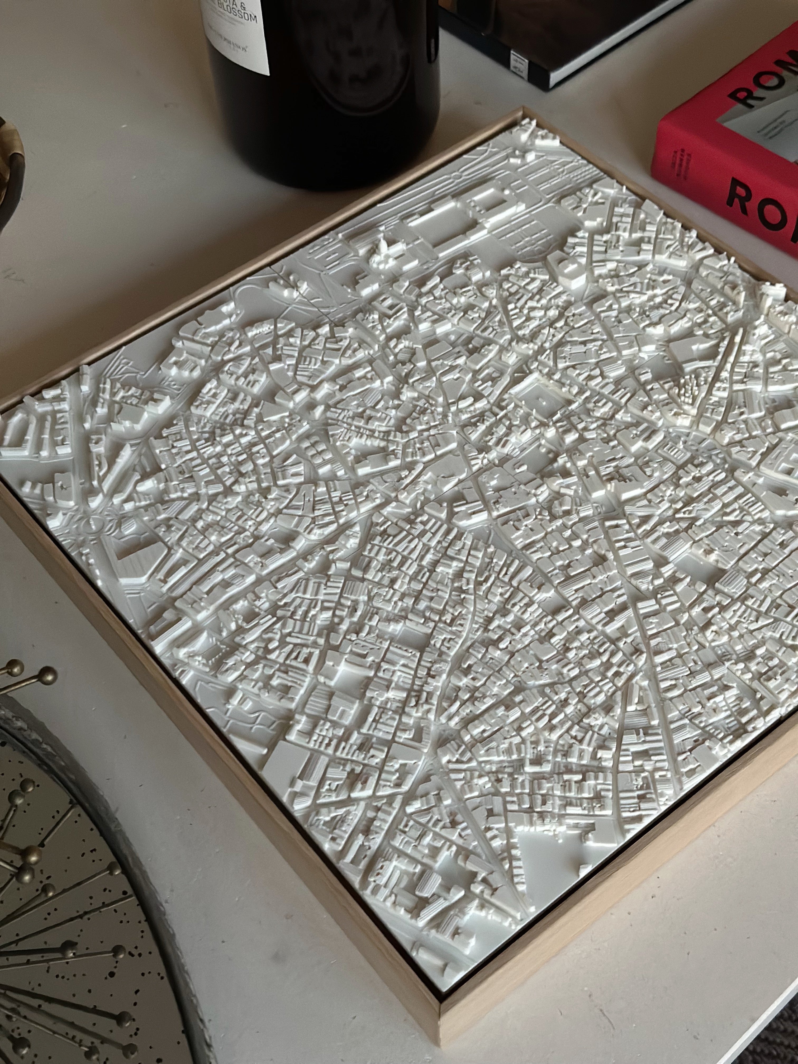 White 3D city map wall art on a table, detailed streets and buildings, modern decor piece.