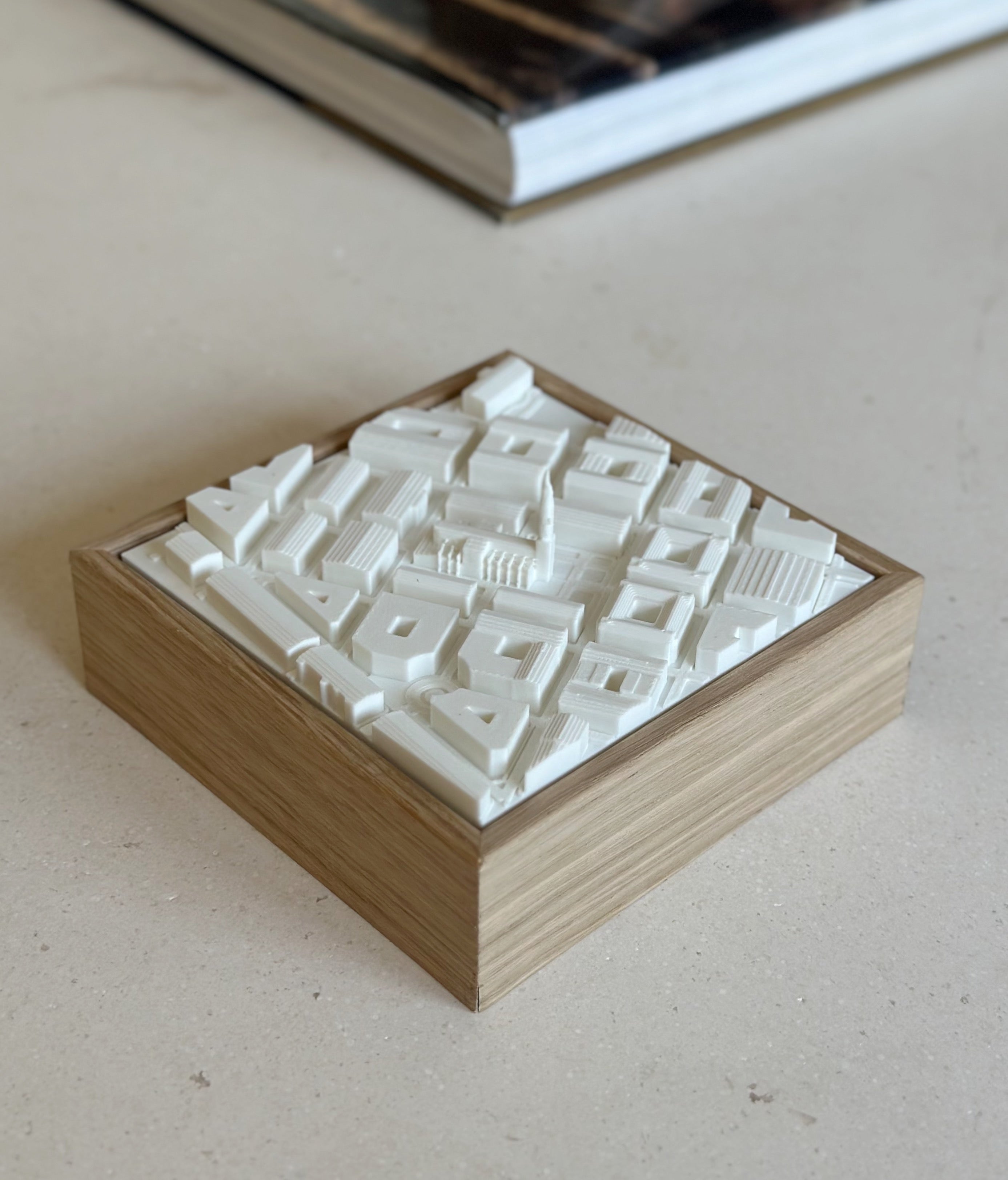 3D city map artwork in a wooden frame, minimalist urban decor on a beige table.