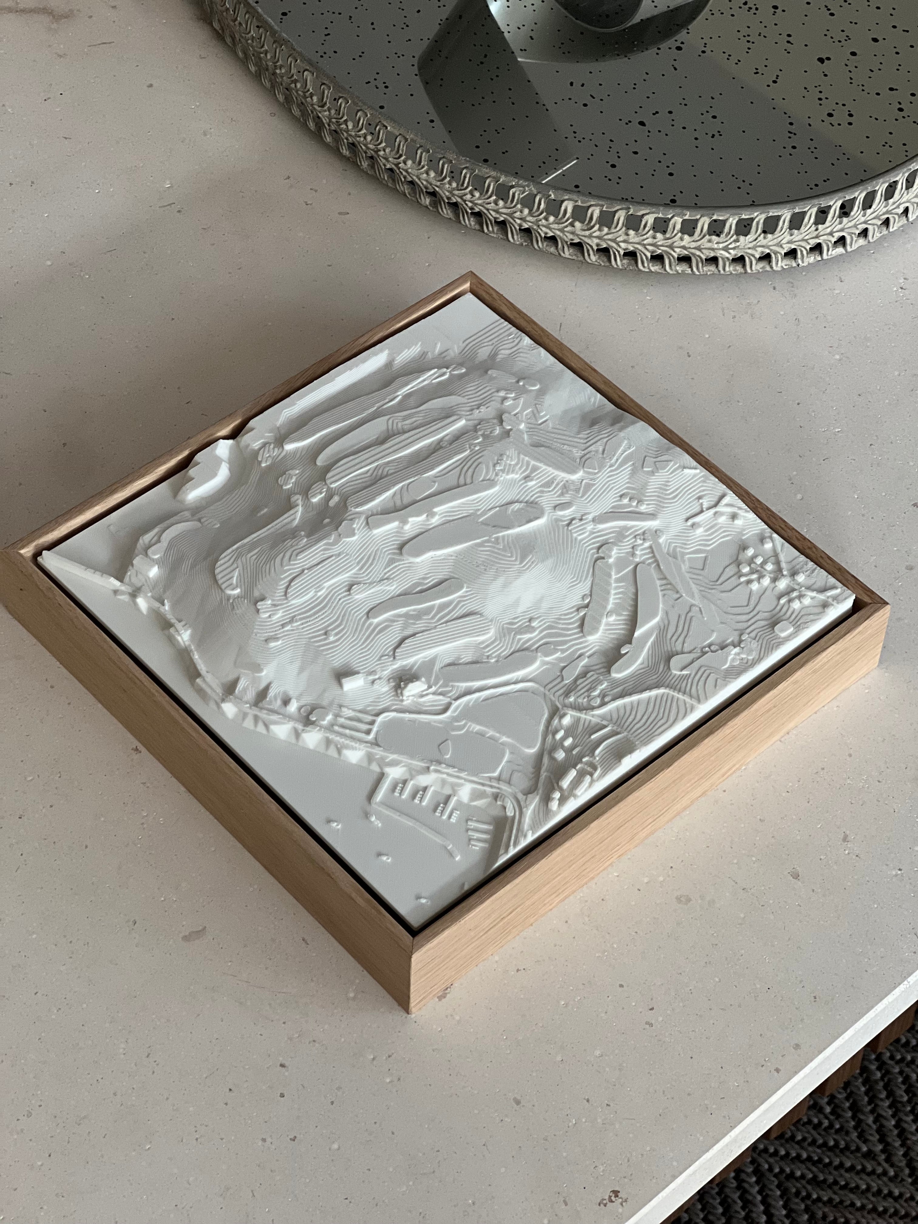 Modern 3D city map wall art with topographic details in a wooden frame on a table