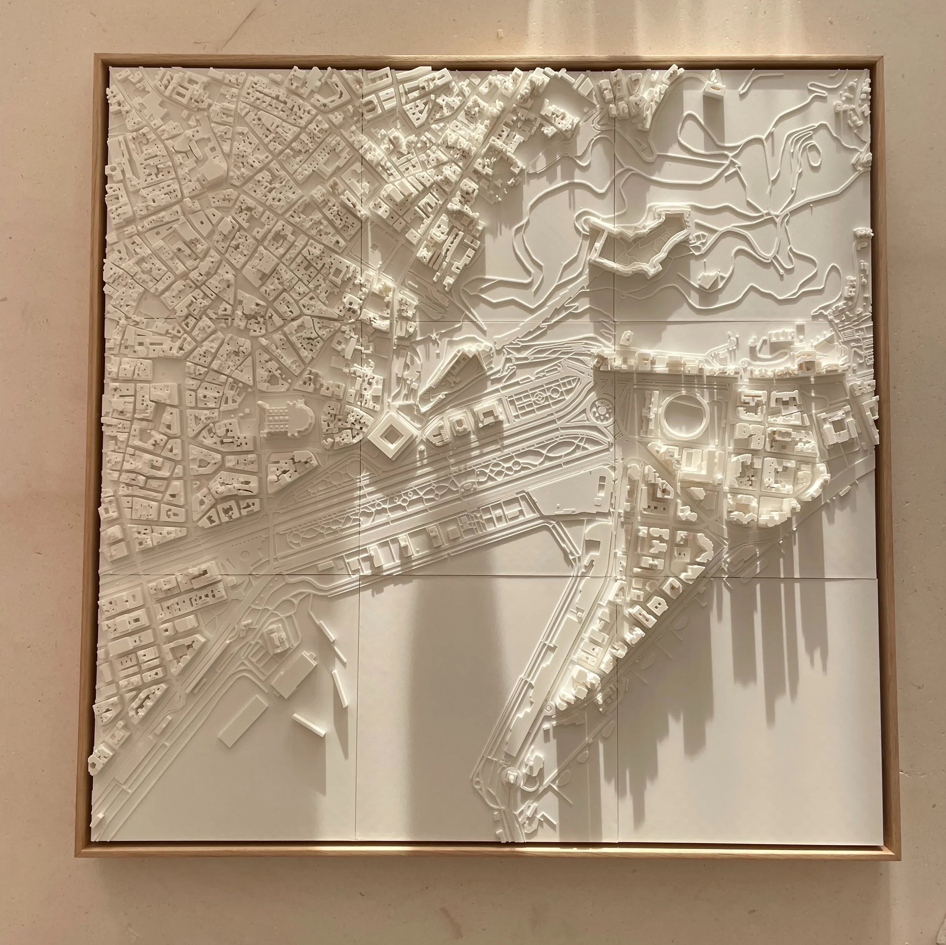 3D wall art map of a city with detailed buildings and streets in white relief