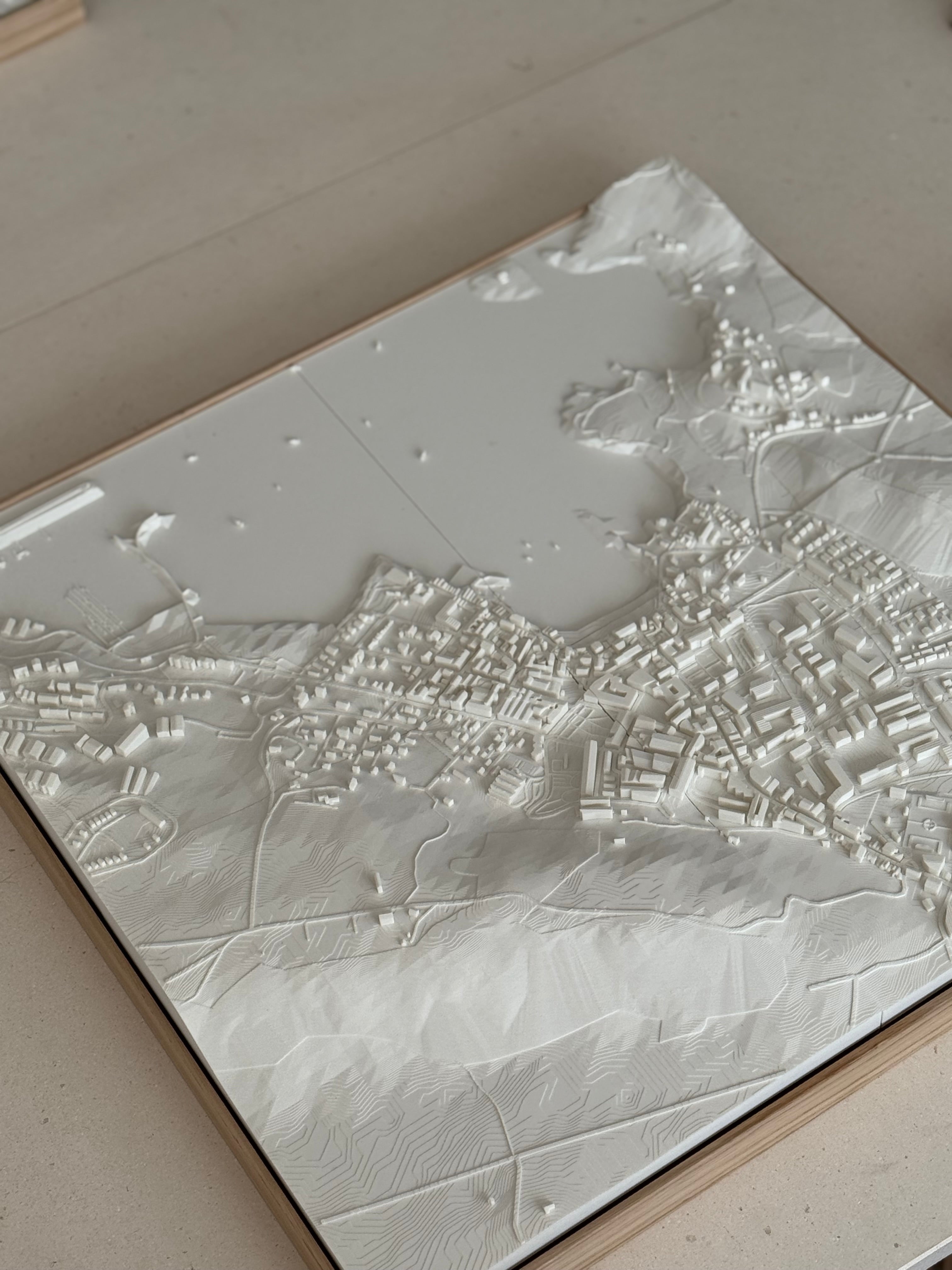 3D city map wall art with raised topography and detailed urban layout in white.