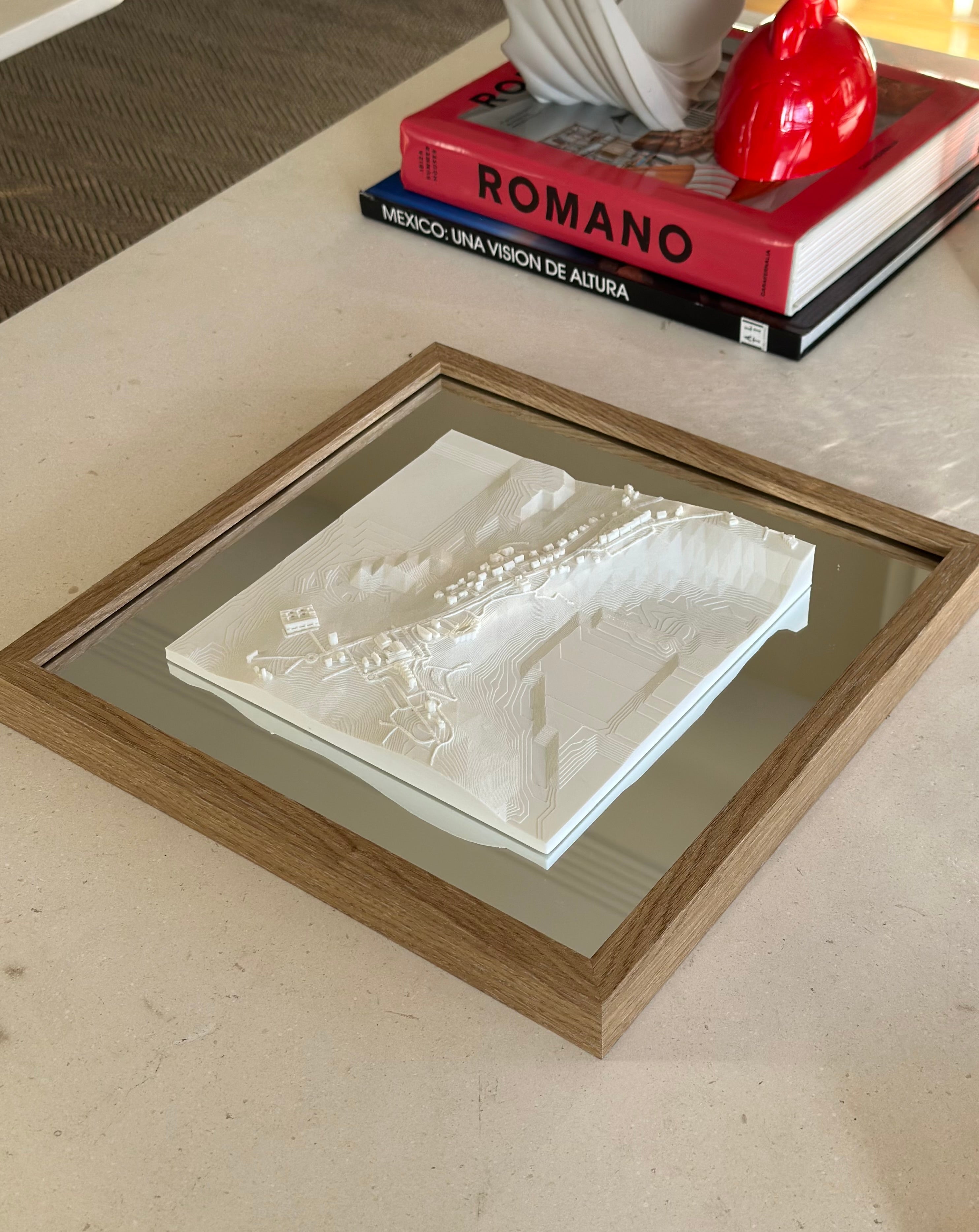 Framed 3D city map artwork on coffee table with books and decor in the background