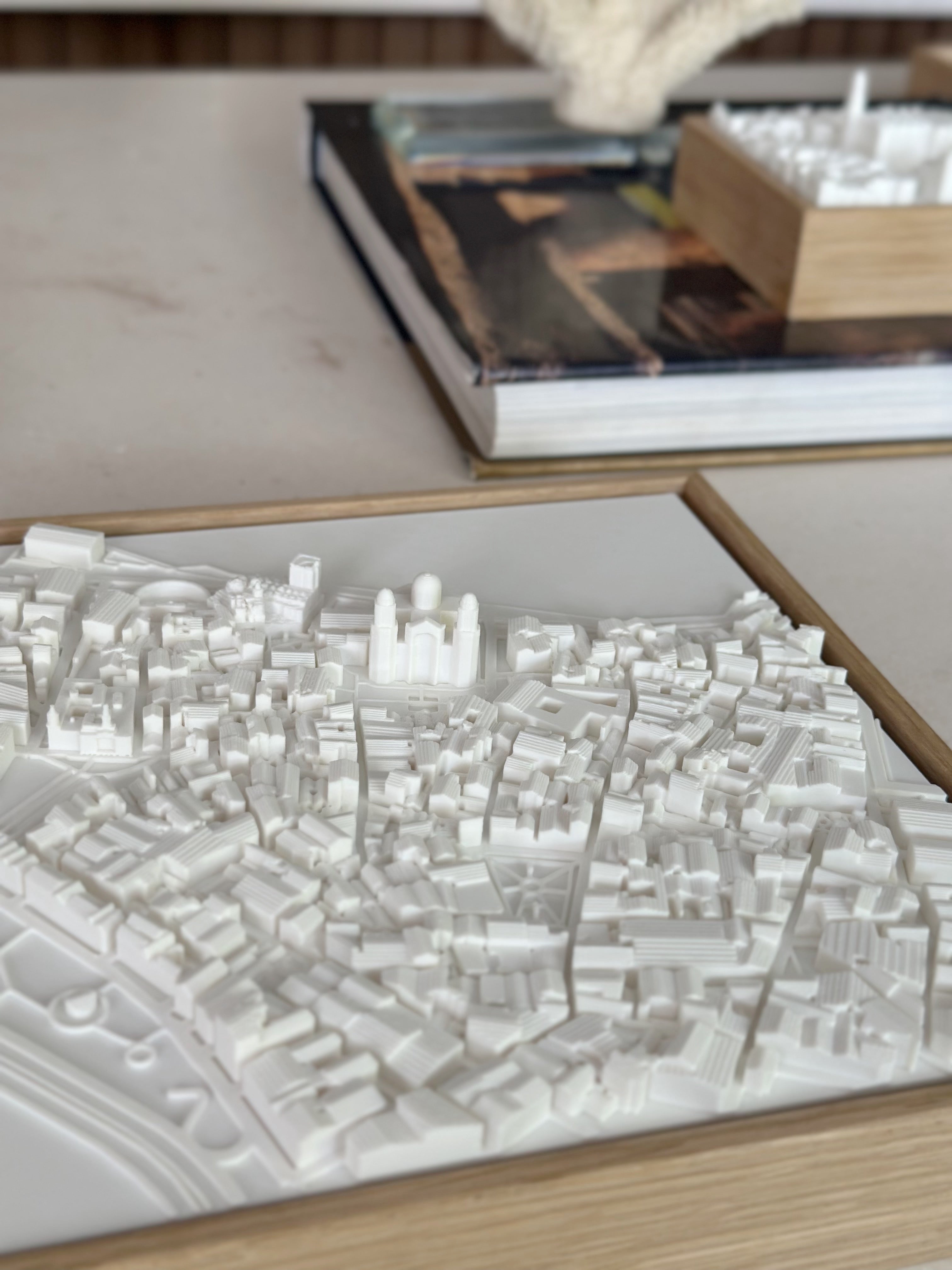 3D city map art in white with wooden frame, decorative urban decor on modern table.