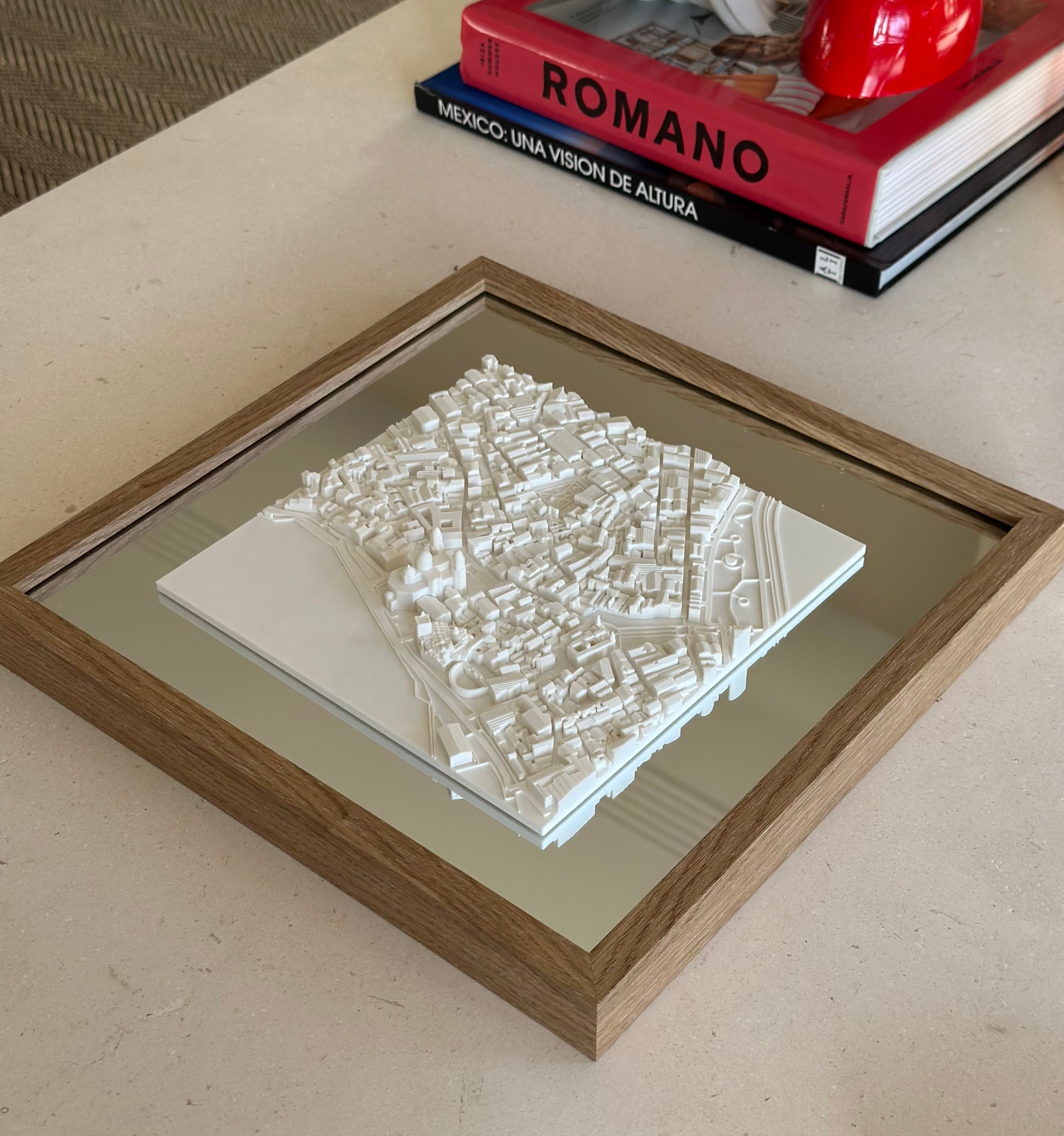 Framed 3D city map decor piece with white buildings on a table, modern home setting