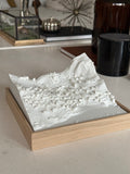 3D city map wall art with detailed buildings and terrain in a wooden frame on a modern table