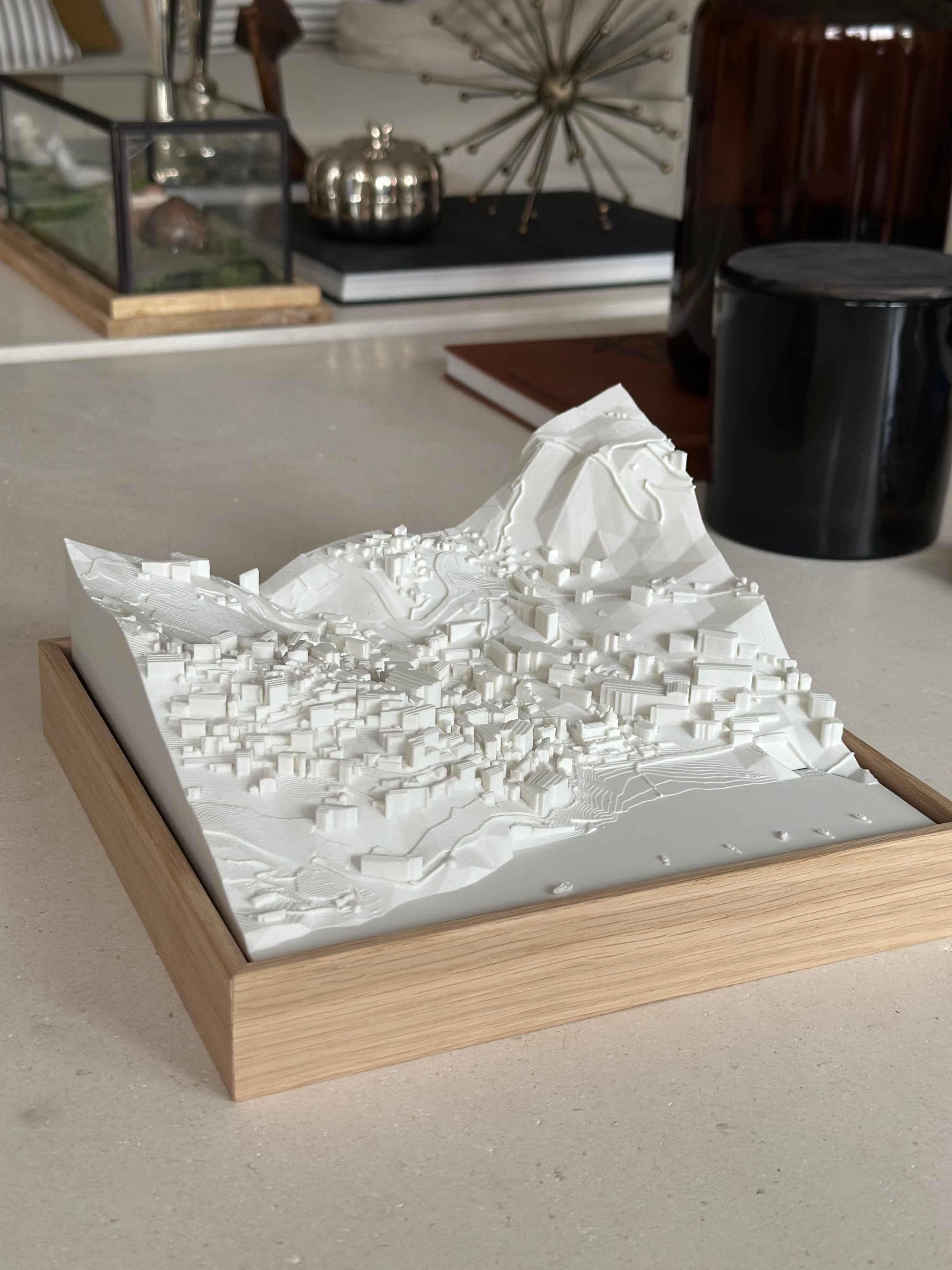 3D city map wall art with detailed buildings and terrain in a wooden frame on a modern table