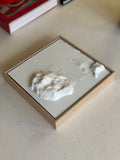 3D city map wall art in a wooden frame on a light surface, topographic decor piece