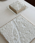 3D city map wall art models in white, featuring detailed urban landscapes on a tabletop.