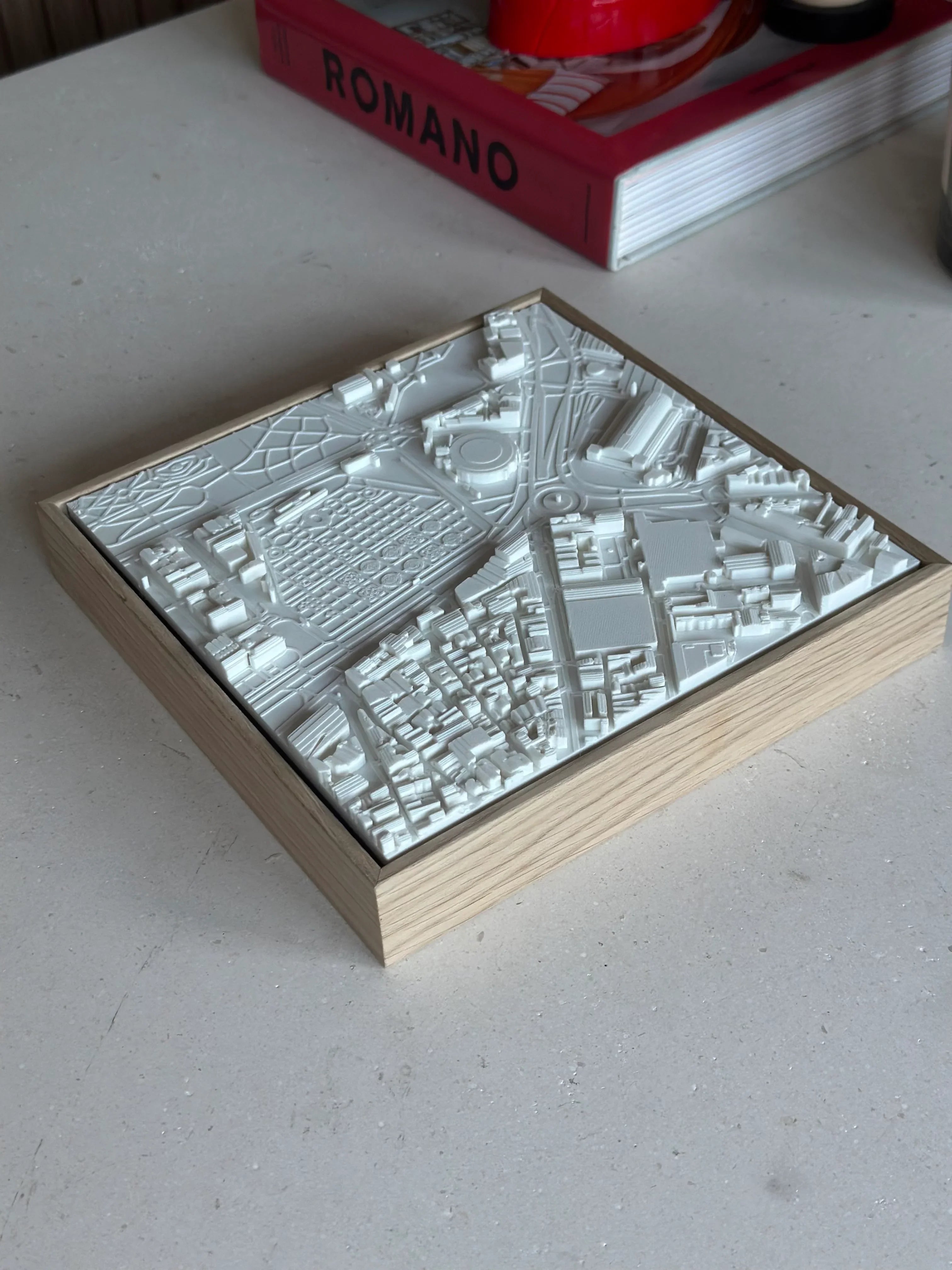 Decorative 3D city map wall art in a wooden frame on a minimalist table