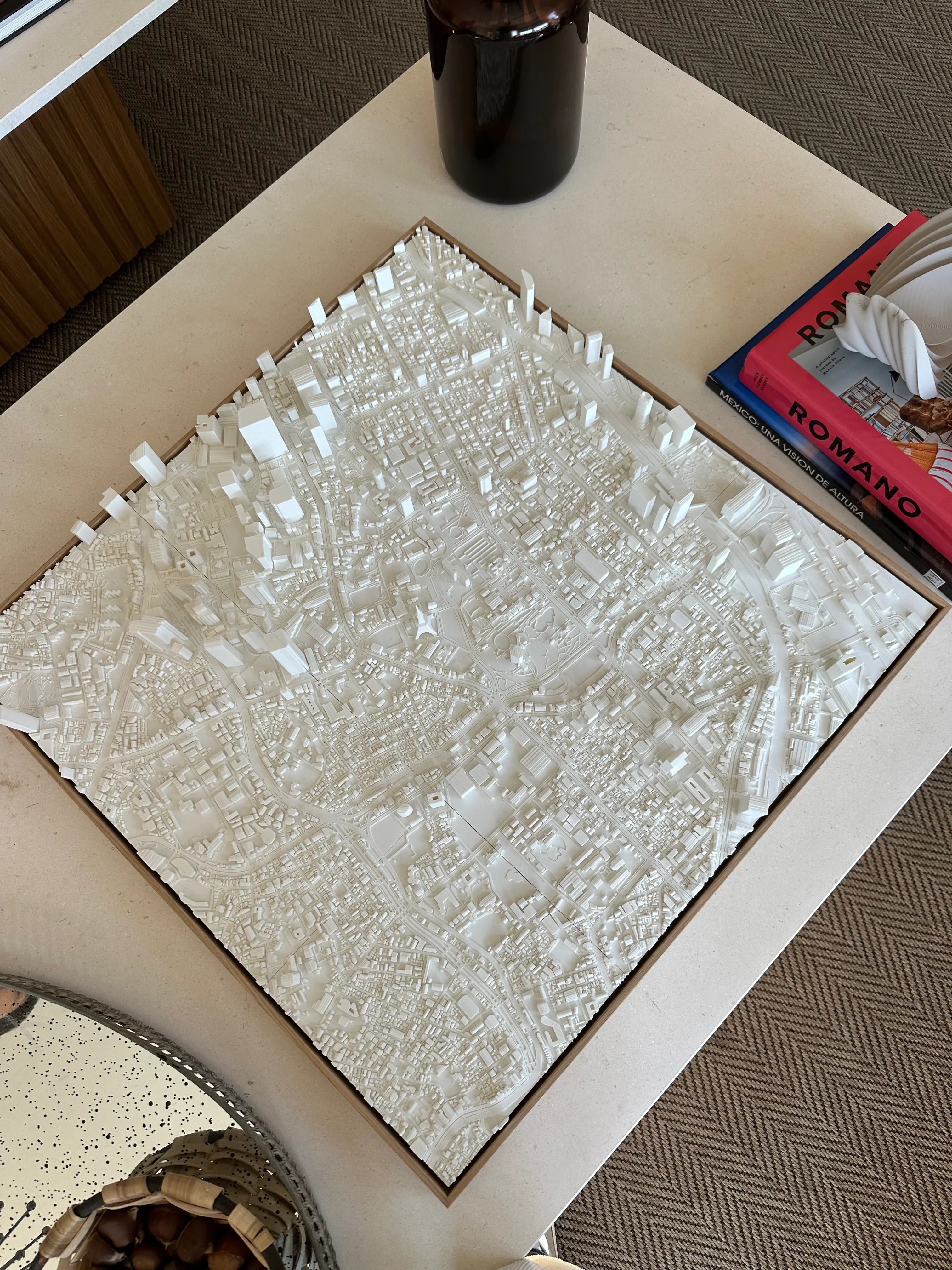 3D city map wall art in white, detailed urban decor on a coffee table with books and decor items
