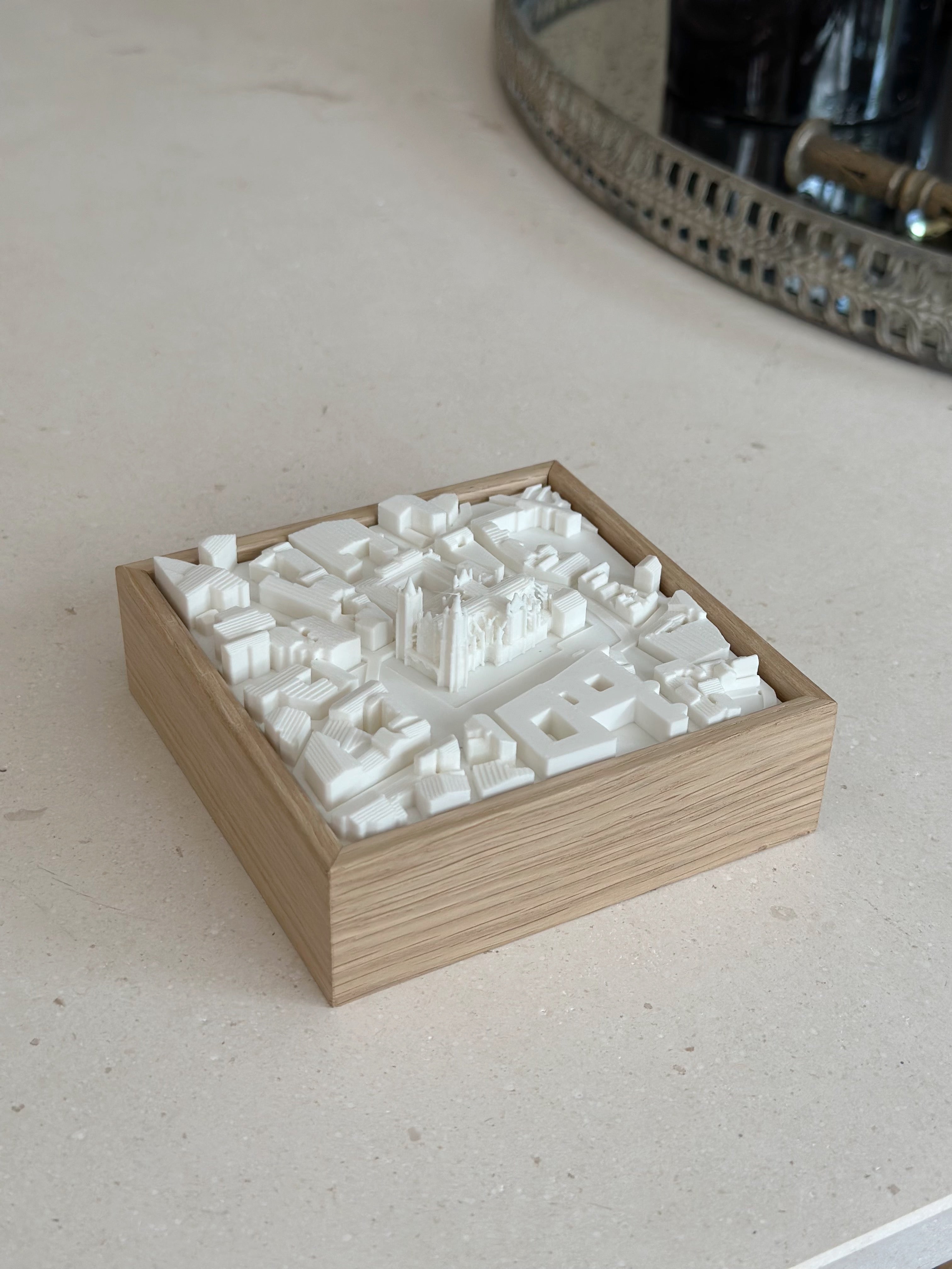 3D city map model in a wooden frame, displayed on a light stone surface