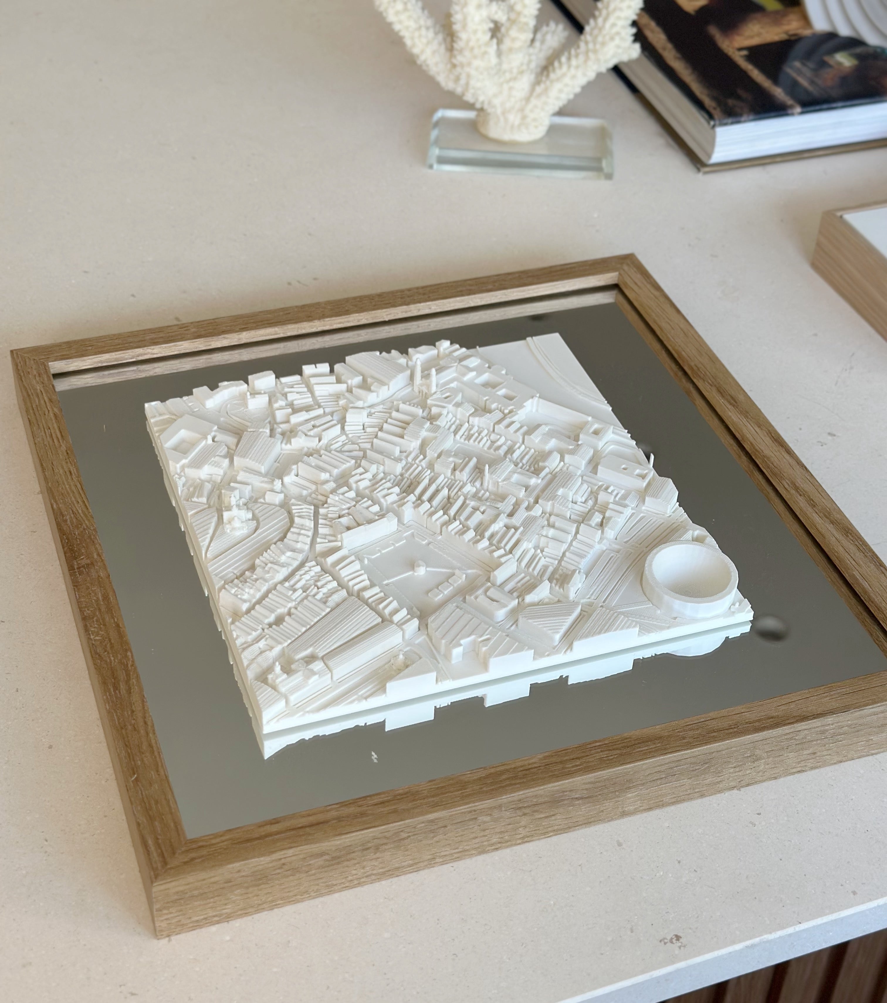 Framed 3D city map wall art with detailed white buildings on a modern tabletop.