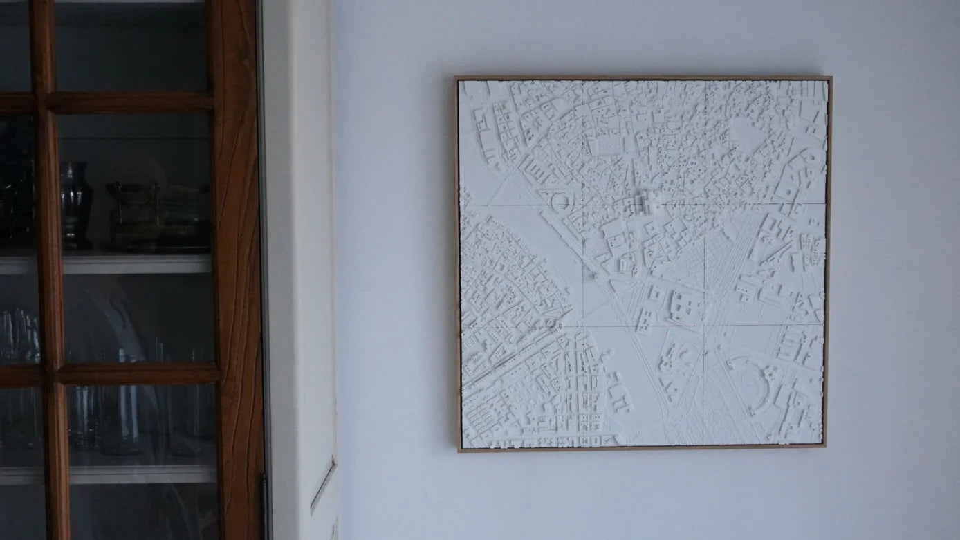 White 3D city map wall art with intricate urban details hanging in a modern interior.