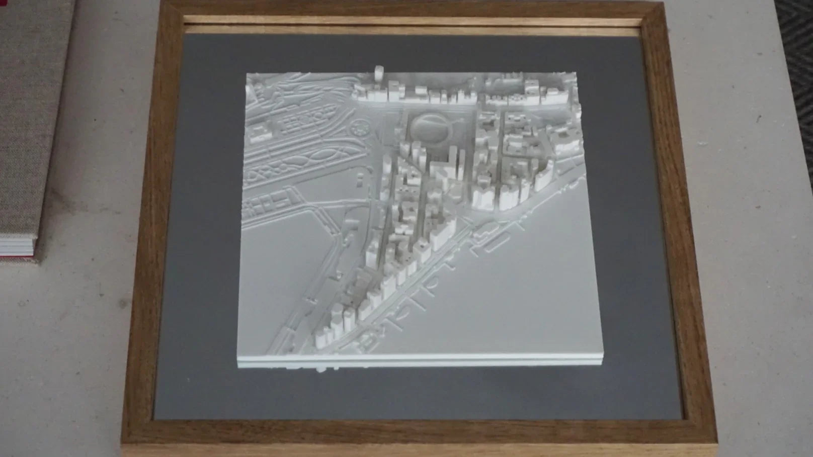 Framed 3D city map art with white buildings on a gray background, modern wall decor