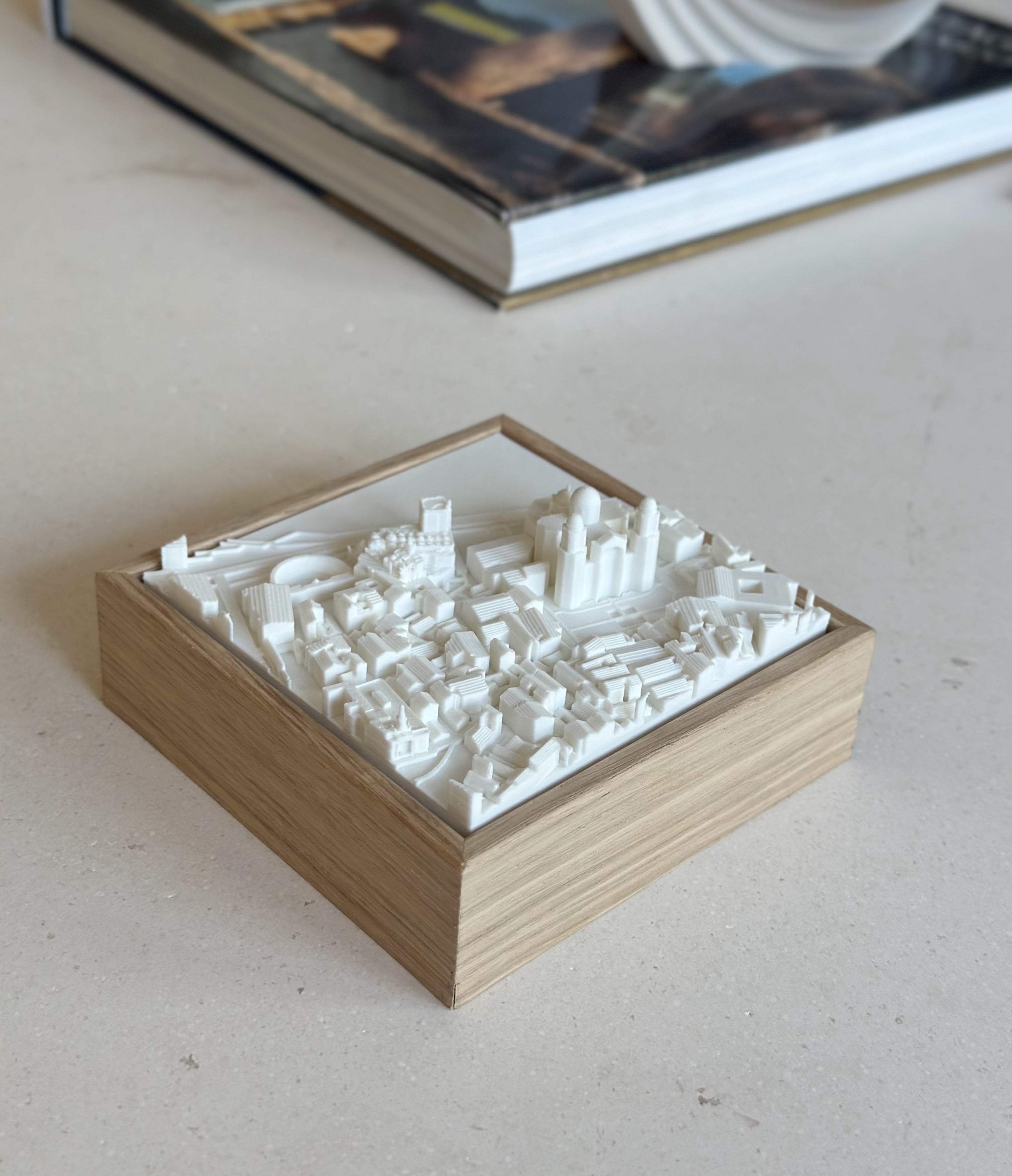 3D city map art in a wooden frame, decorative cityscape sculpture on a table
