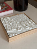 3D city map wall art with white buildings in a wooden frame on a modern table