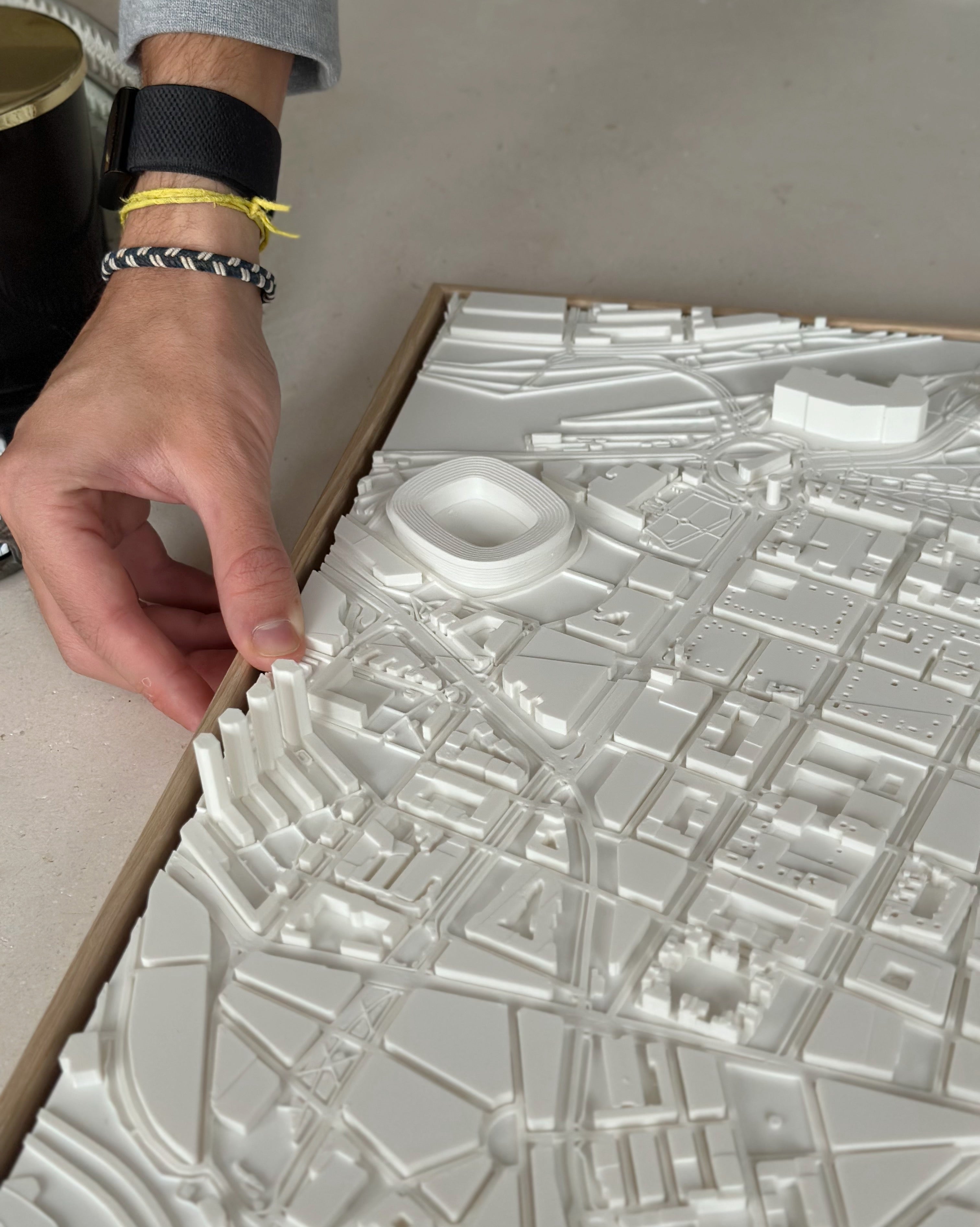 Hand touching detailed 3D city map wall art with white architectural buildings