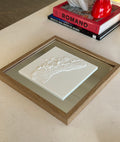 Framed 3D city map artwork on coffee table with books and decor