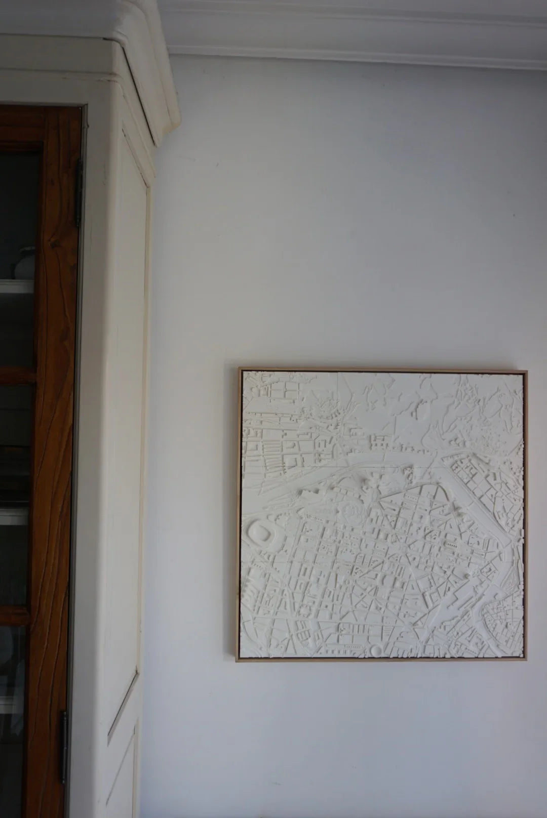 3D city map wall art in white frame, minimalist urban decor hanging on a light wall