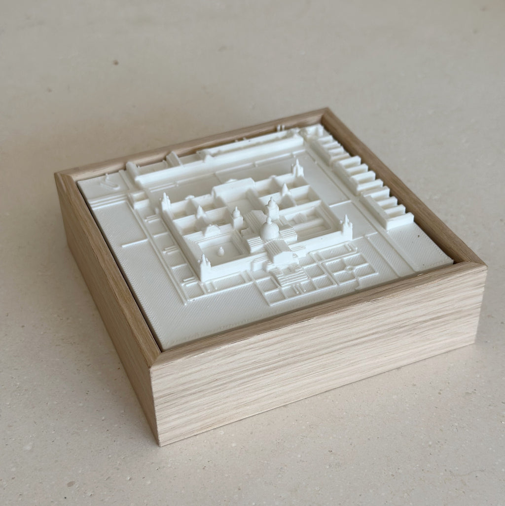 3D city map artwork in a wooden frame, white architectural model on beige surface