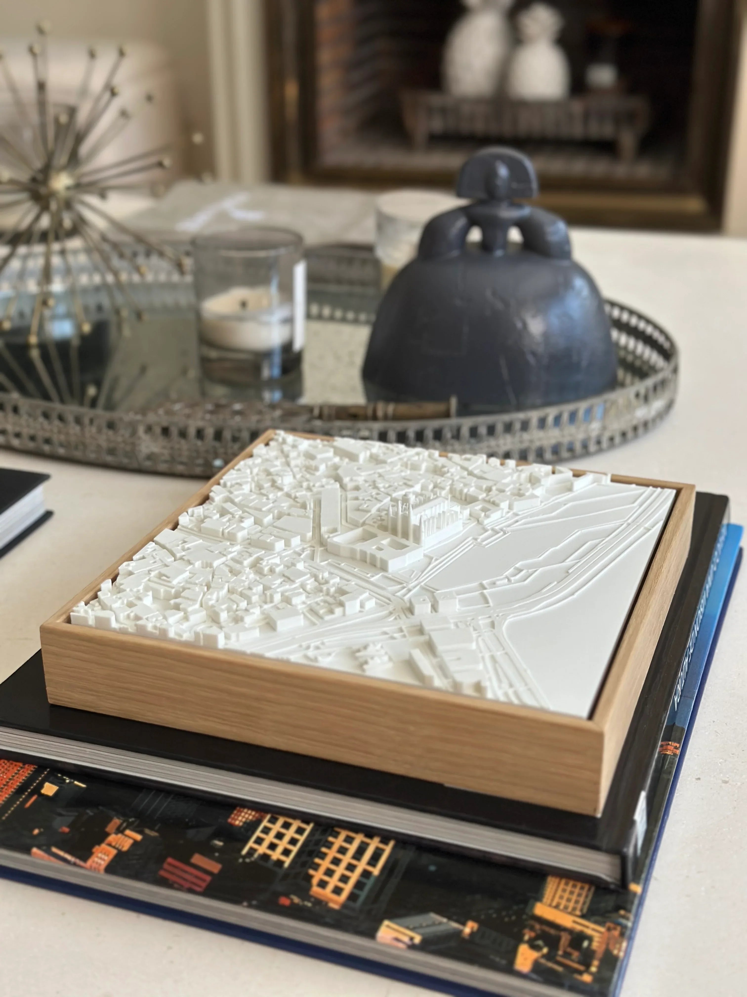 Modern living room table with 3D city map wall art in wooden frame, decorative books and candles