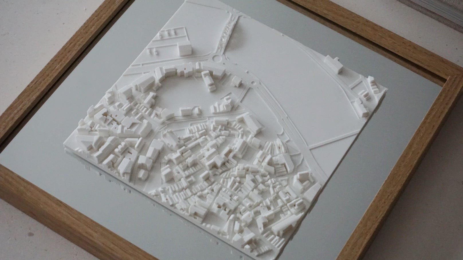 Framed 3D city map in white, showing detailed urban buildings and streets