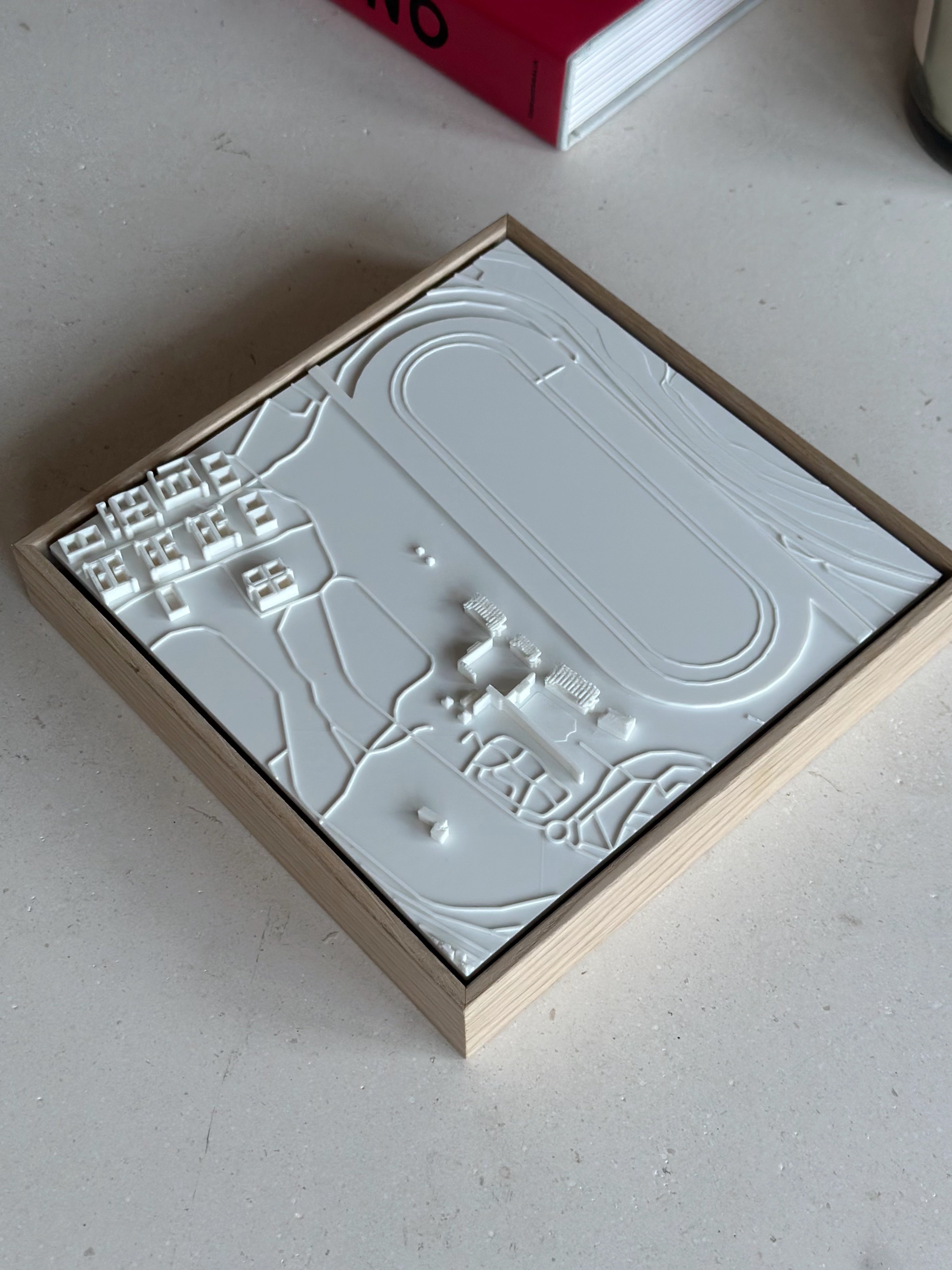 Framed white 3D city map wall art with architectural details on a minimalist table