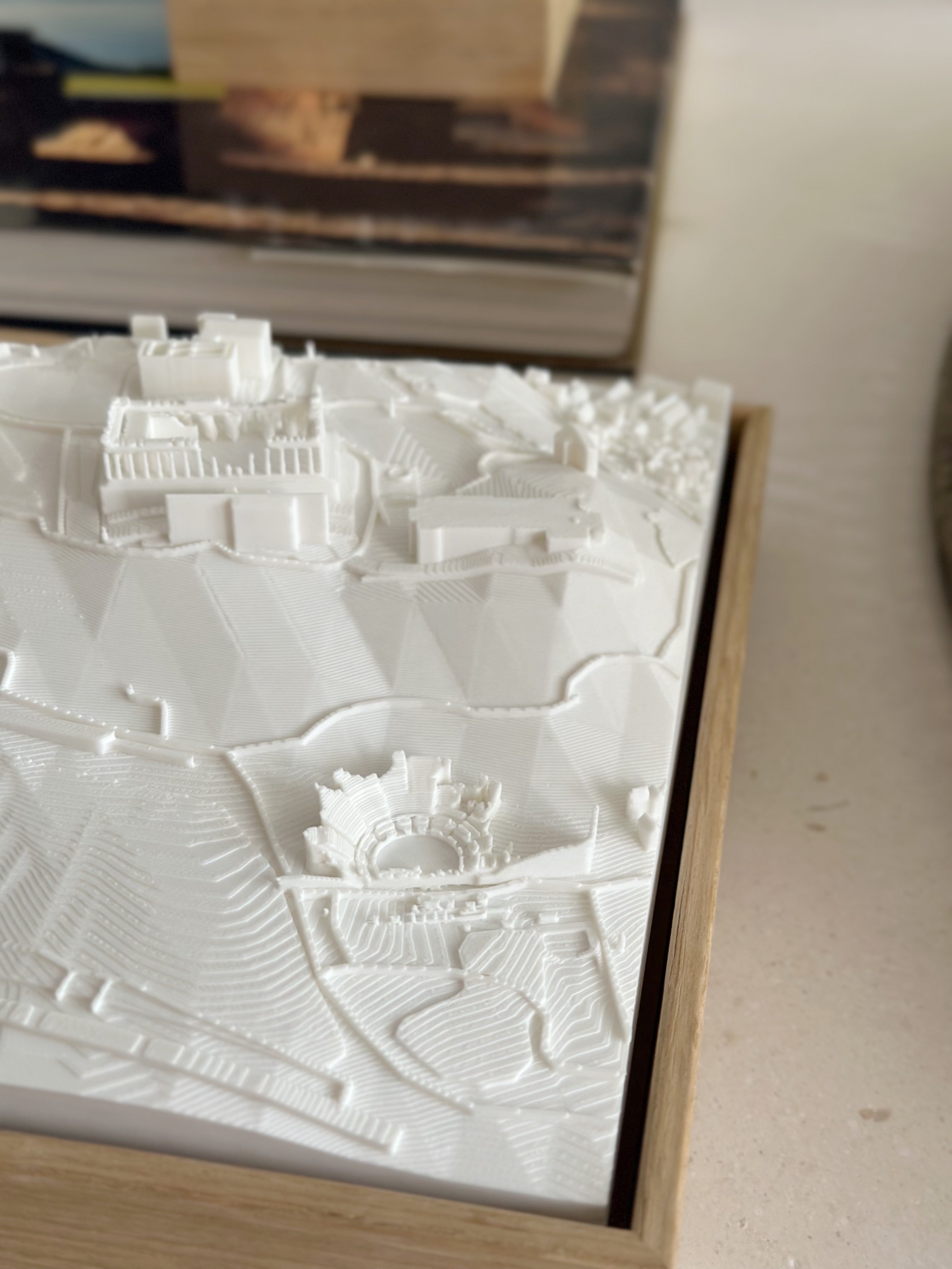 White 3D city map wall art in a wooden frame, showing detailed architectural landscape.