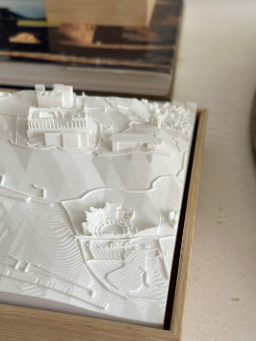 White 3D city map wall art in a wooden frame, showing detailed architectural landscape.