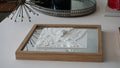 3D city map artwork in wood frame, displayed on a modern white table, home decor