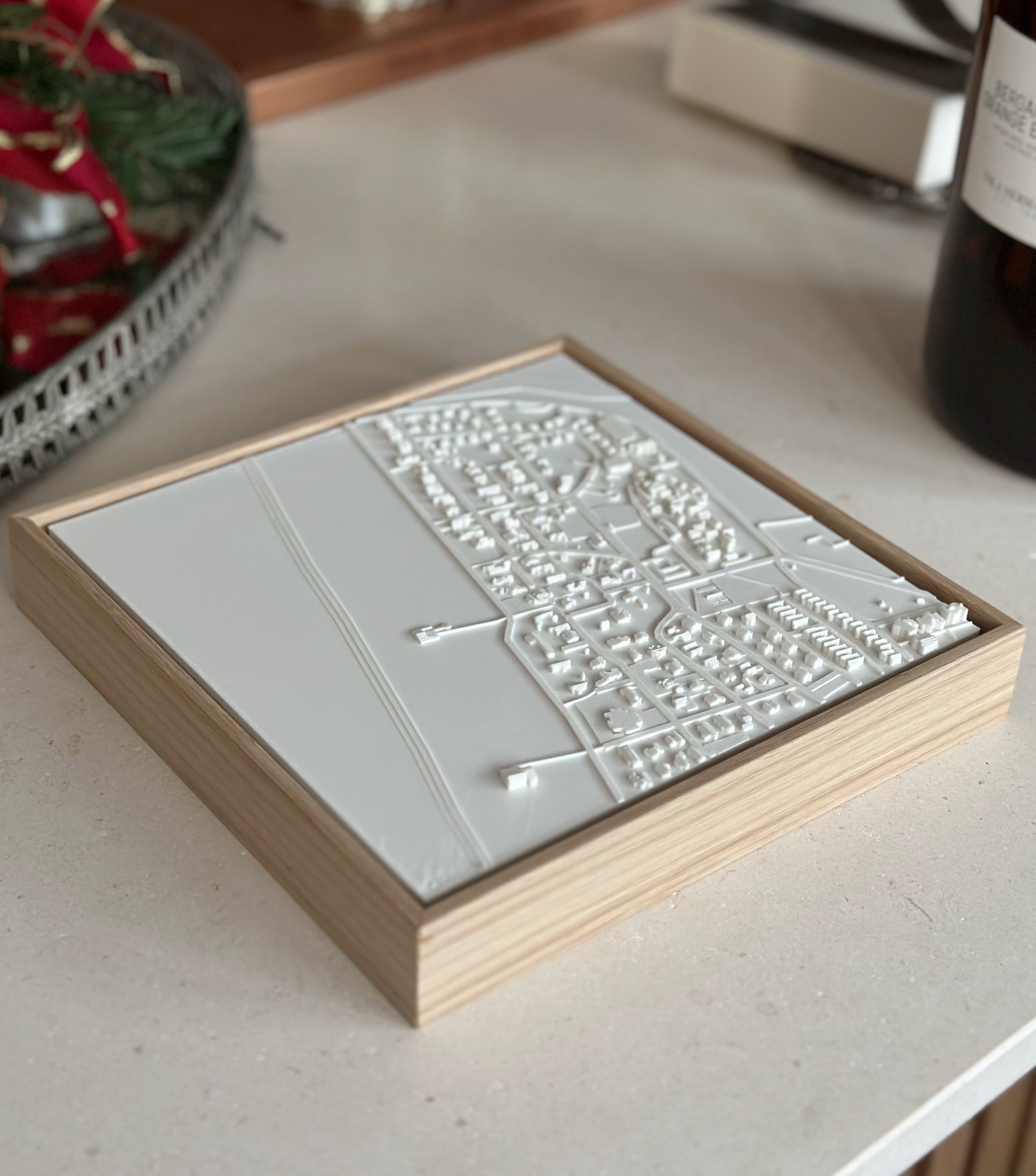 3D city map wall art in a light wooden frame, displayed on a modern countertop