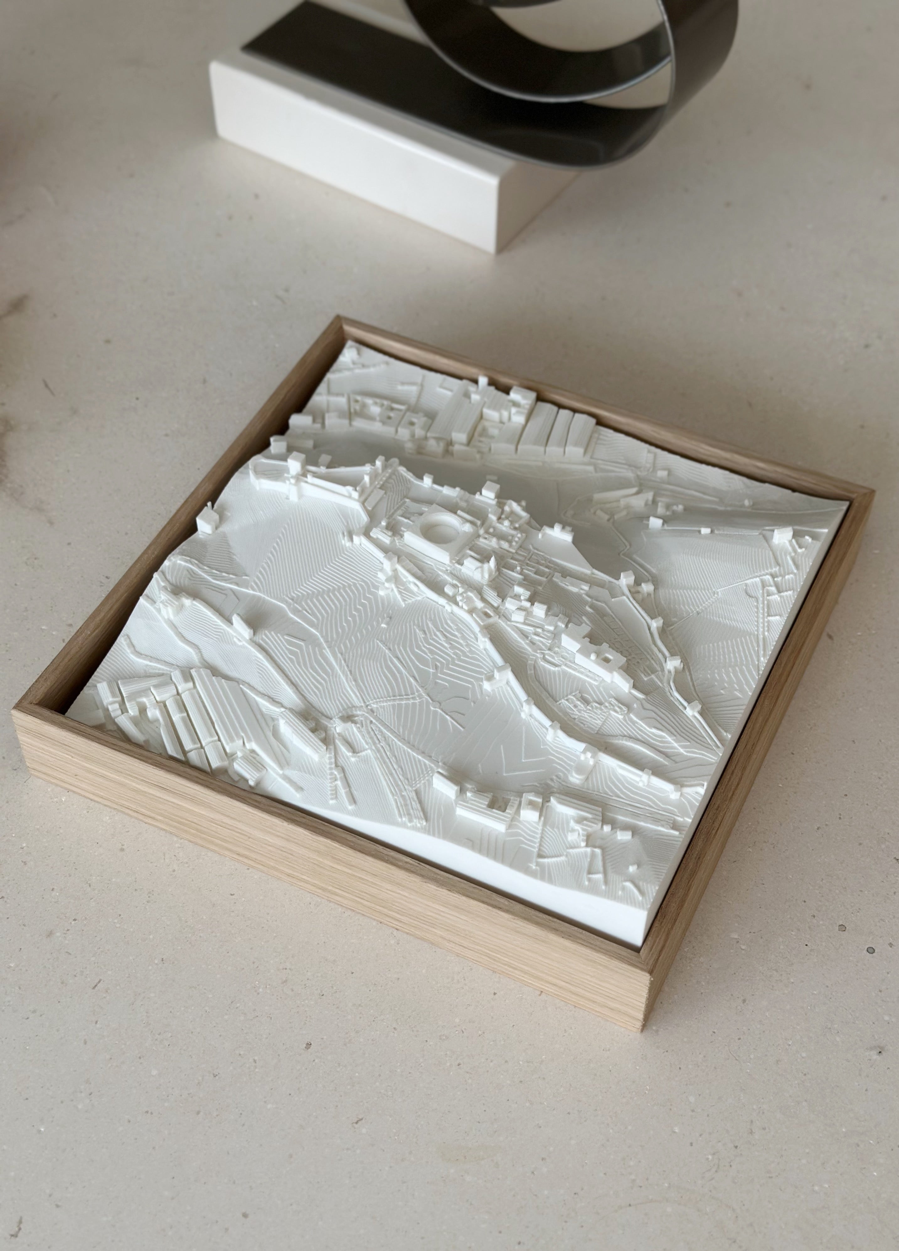 3D city map wall art in a wooden frame, modern decorative piece on a light surface