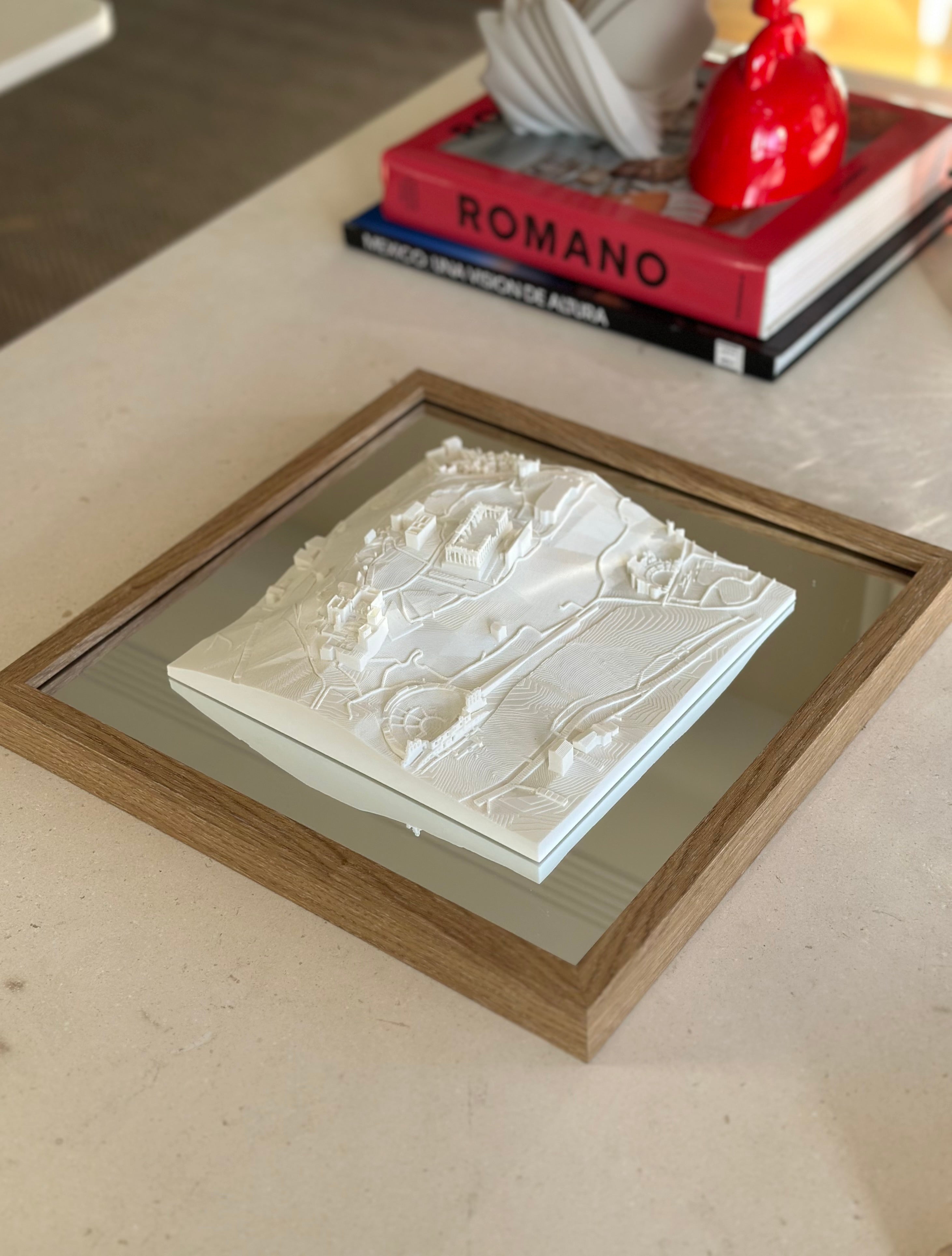 Framed 3D city map artwork displayed on a modern coffee table with decor books.