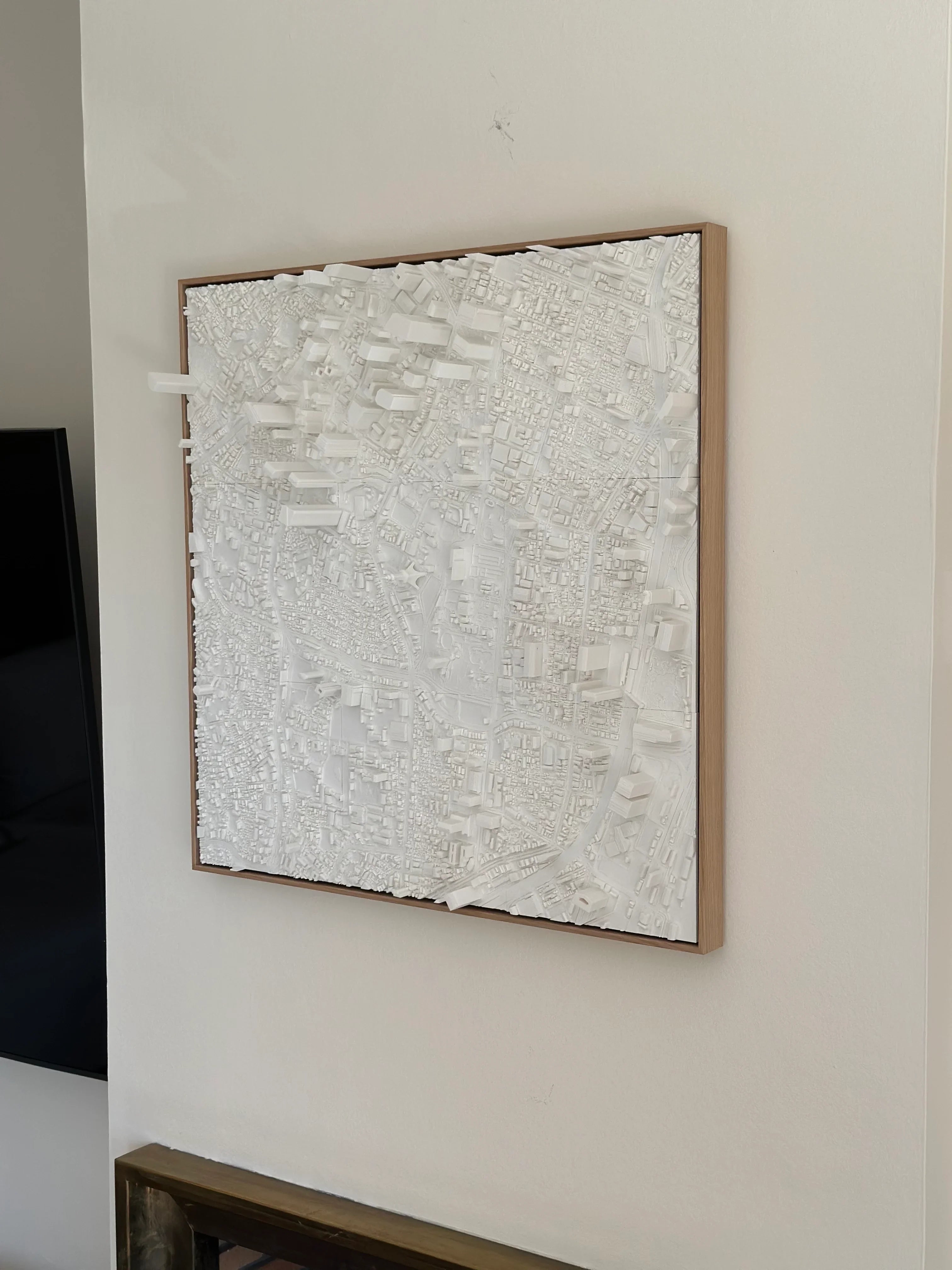 3D city map wall art in white, framed and mounted on a modern interior wall