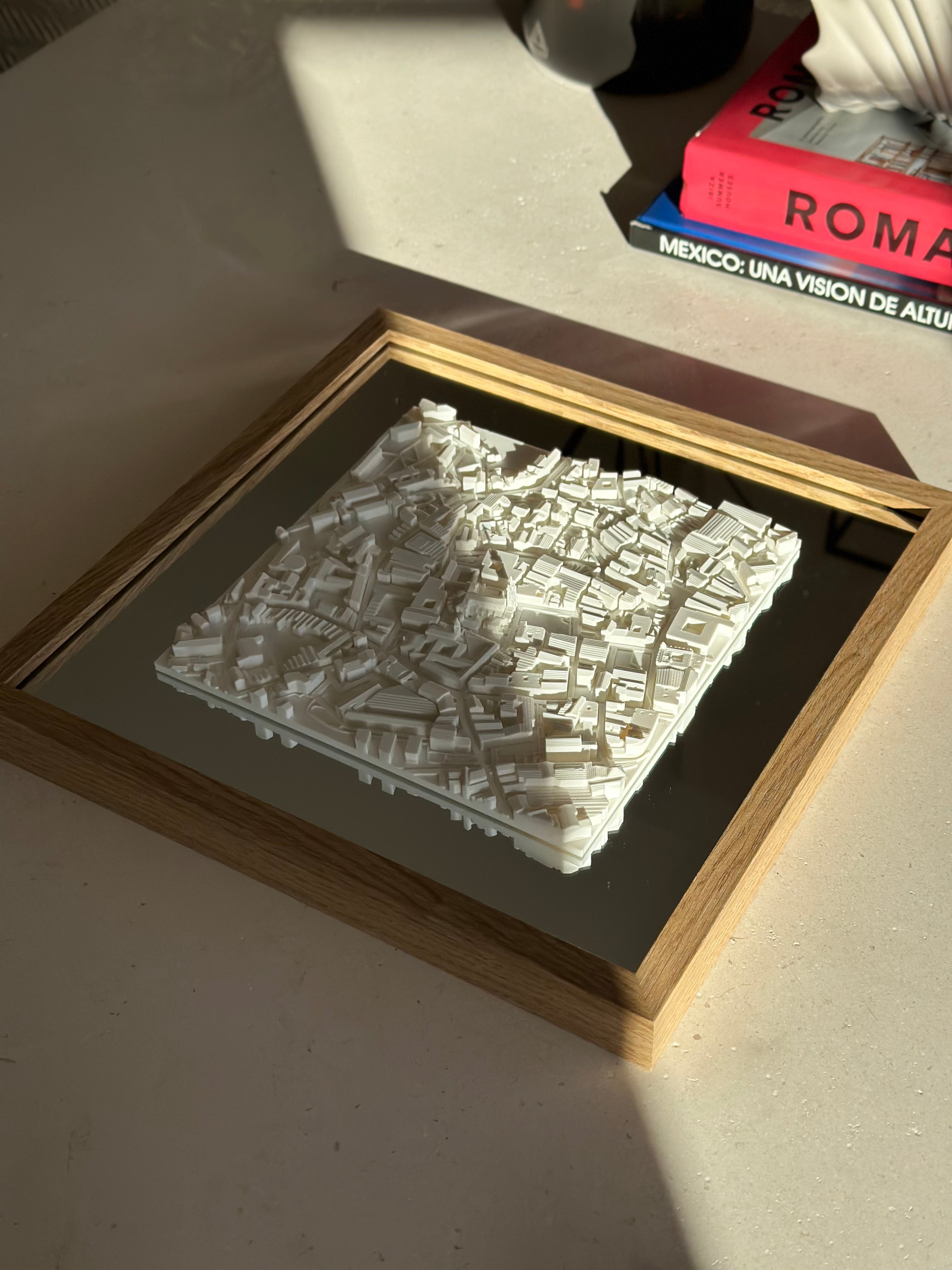Framed 3D city map decor piece on a table, illuminated by natural sunlight
