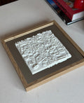 Framed 3D city map artwork with white topography on a wooden frame, tabletop decor