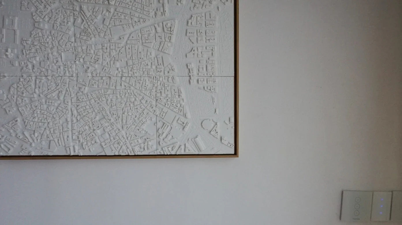 3D city map wall art with white raised details on a minimalist interior wall