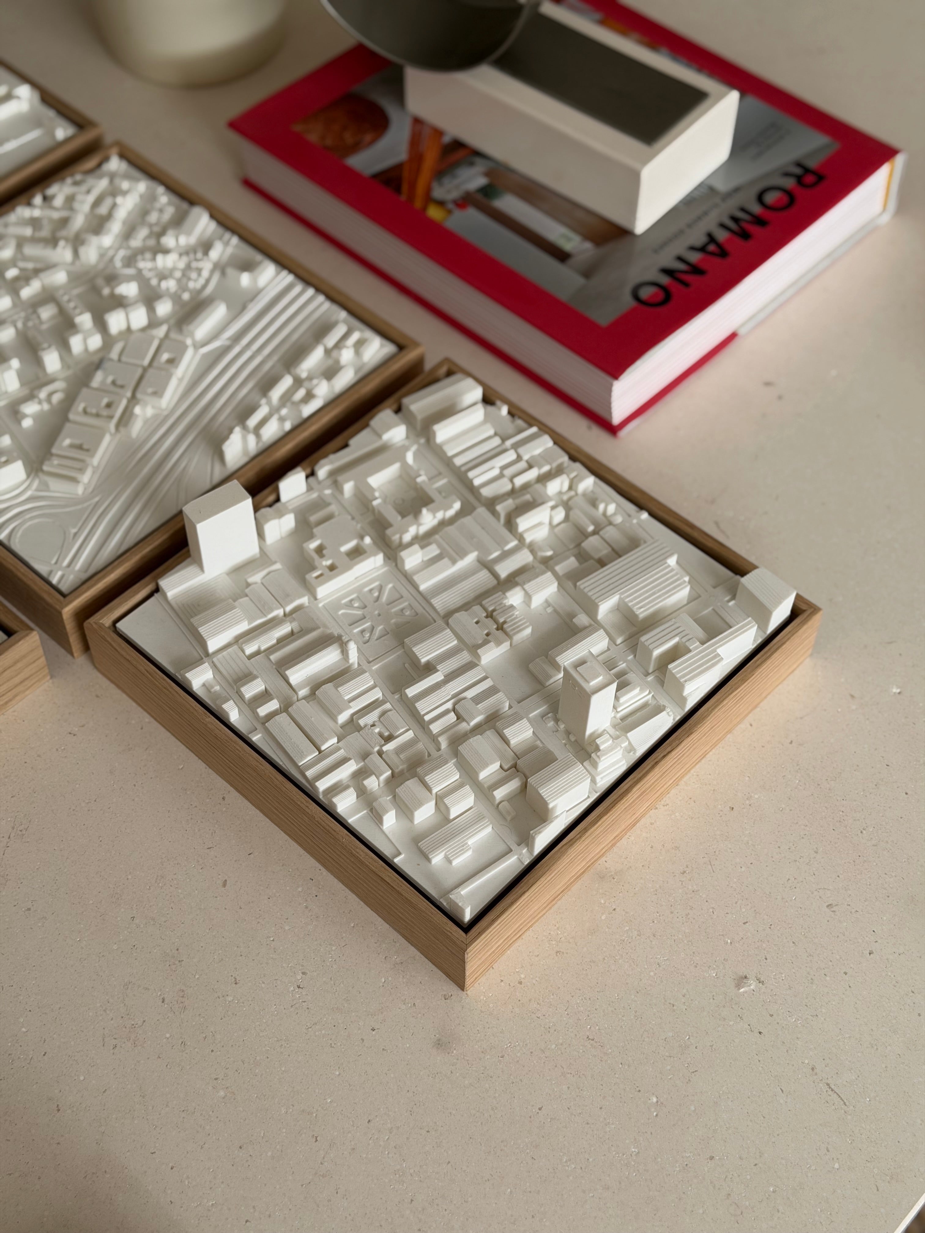 3D city map wall art in a wooden frame on a table with a book and decor
