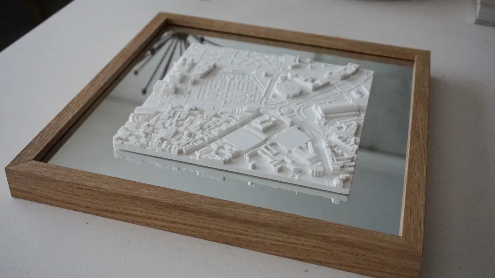 Framed 3D city map wall art with detailed white topographic buildings on a reflective base