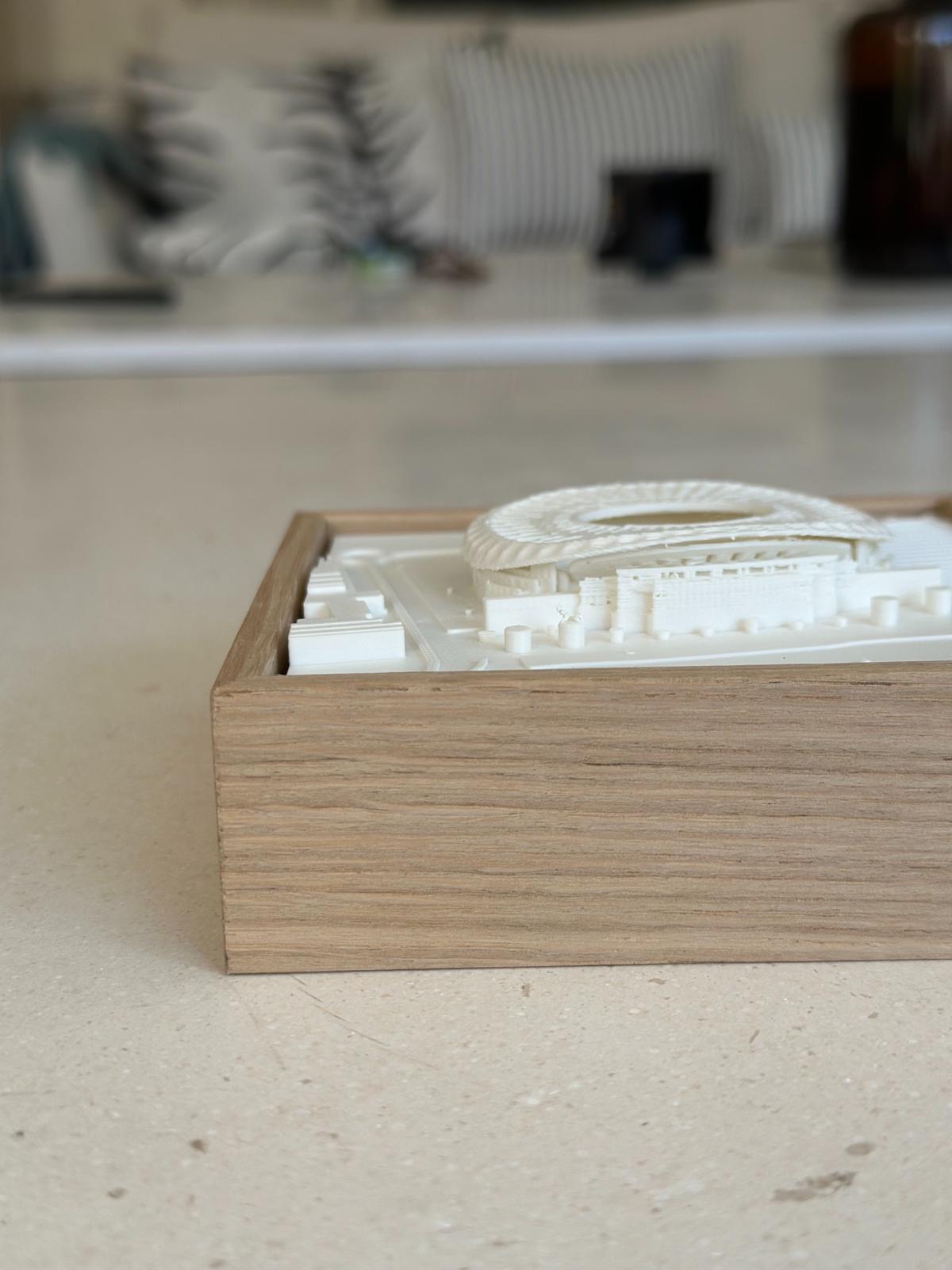 3D city map wall art in a wooden frame on a light surface, close-up view