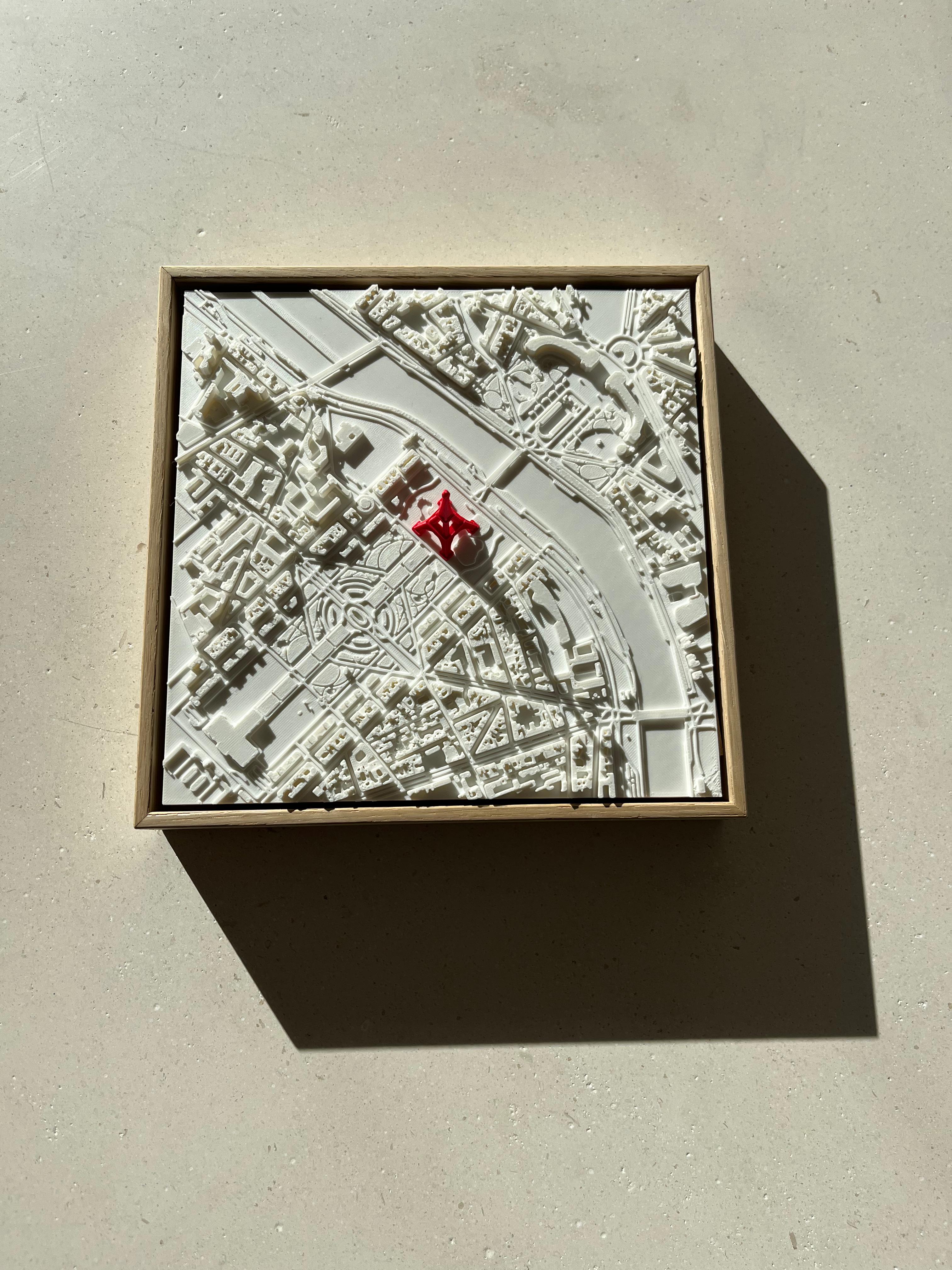 3D city map wall art in a wooden frame, featuring detailed urban streets and a red landmark.