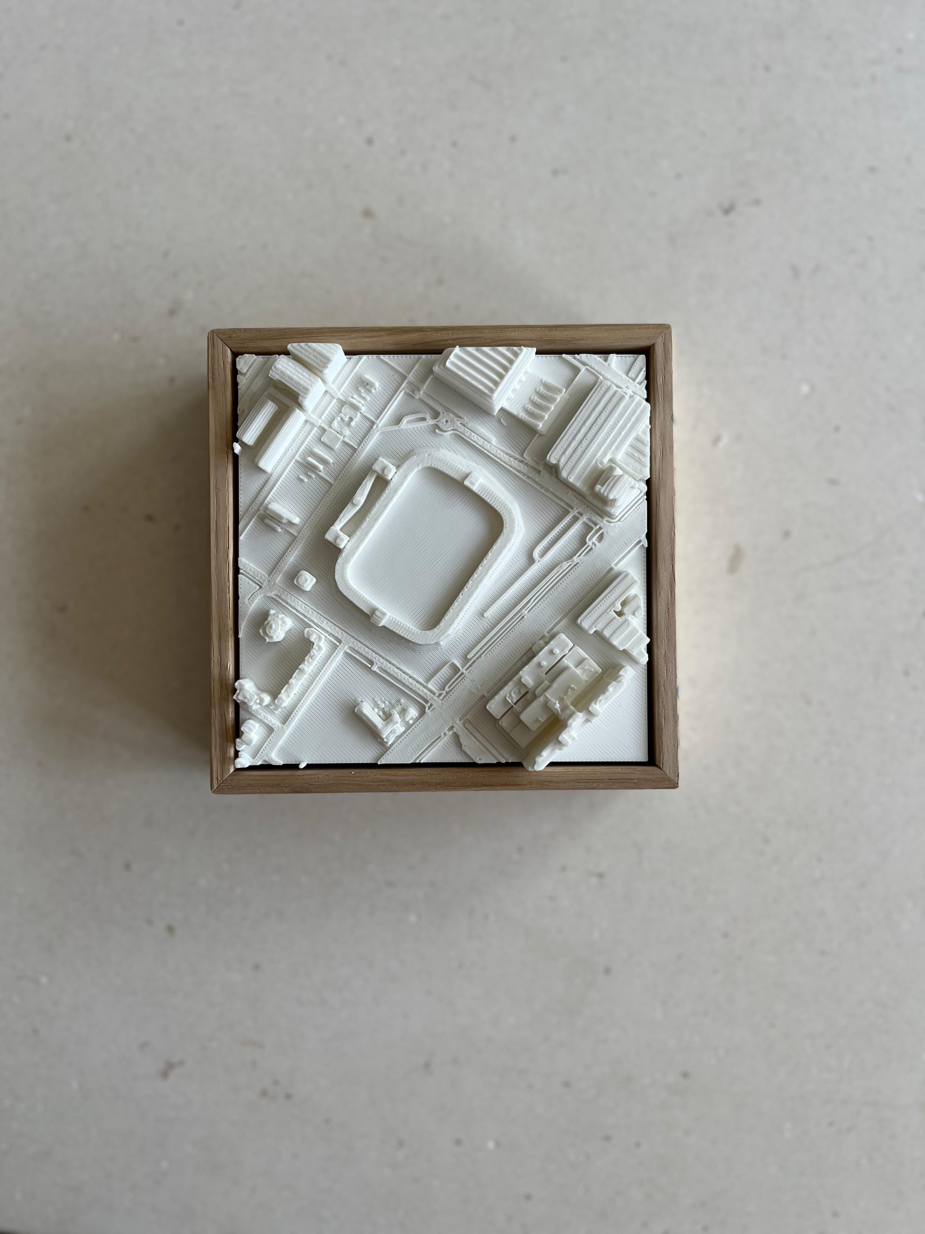 3D city map art in a wooden frame showing urban buildings and streets on a neutral background